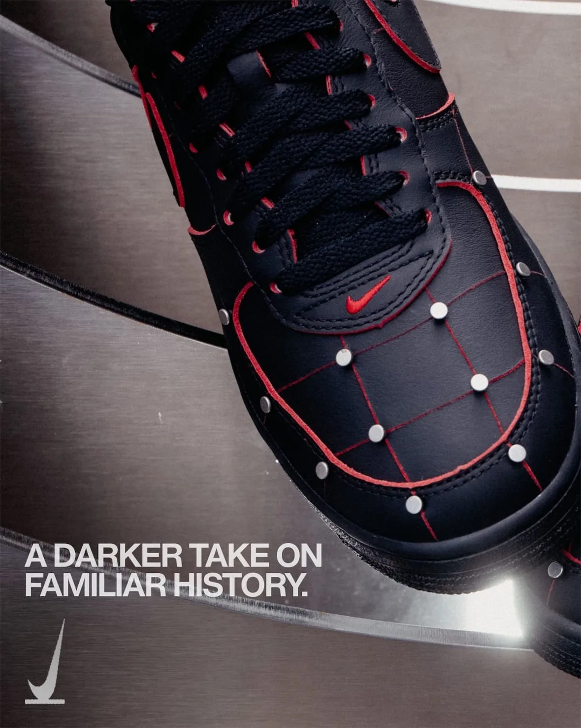 Top-down toe detail, black leather with red stitched grid, silver studs, red swoosh, steel blades behind, Nightmare