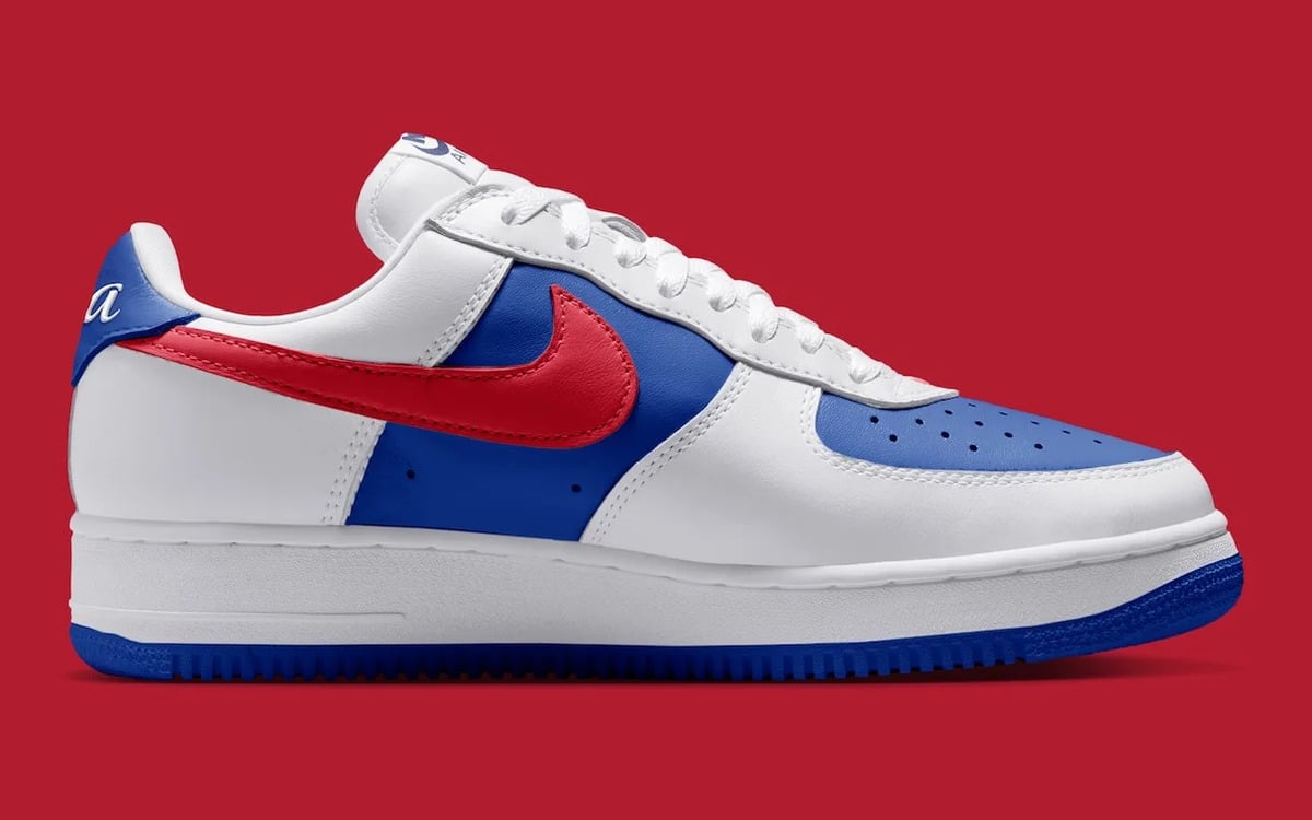 Medial view, red swoosh on blue panel, white leather, blue sole, partial script on heel, Philly
