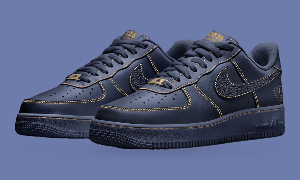 Pair at three-quarter angle, navy leather, gold stitching, textured swoosh, gold 2026 tongue tag, Milwaukee Brewers