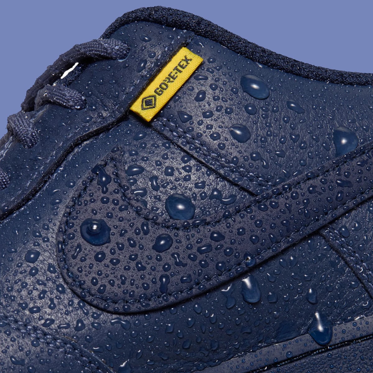 Detail of navy leather covered in water droplets with yellow Gore-Tex tag, Thunder Blue
