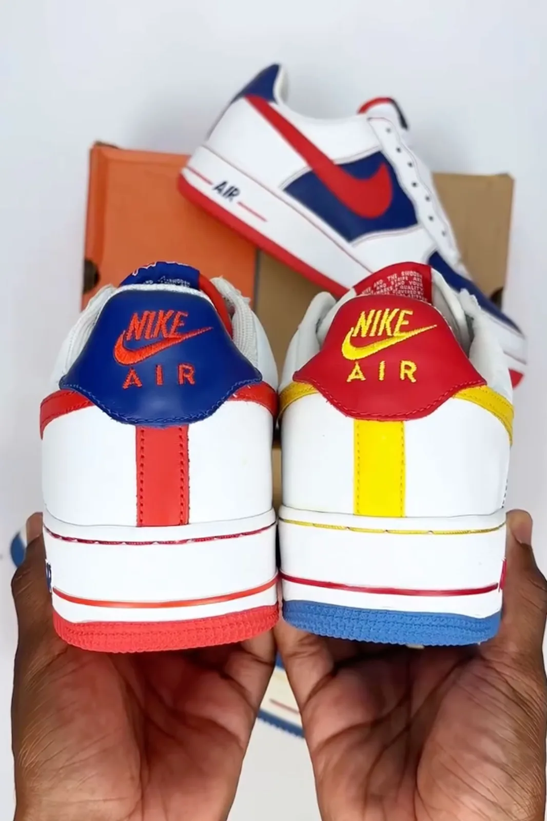 two heel views in hand, nike air text on blue and red tongues with red/yellow stripes, Remix Da Kickz