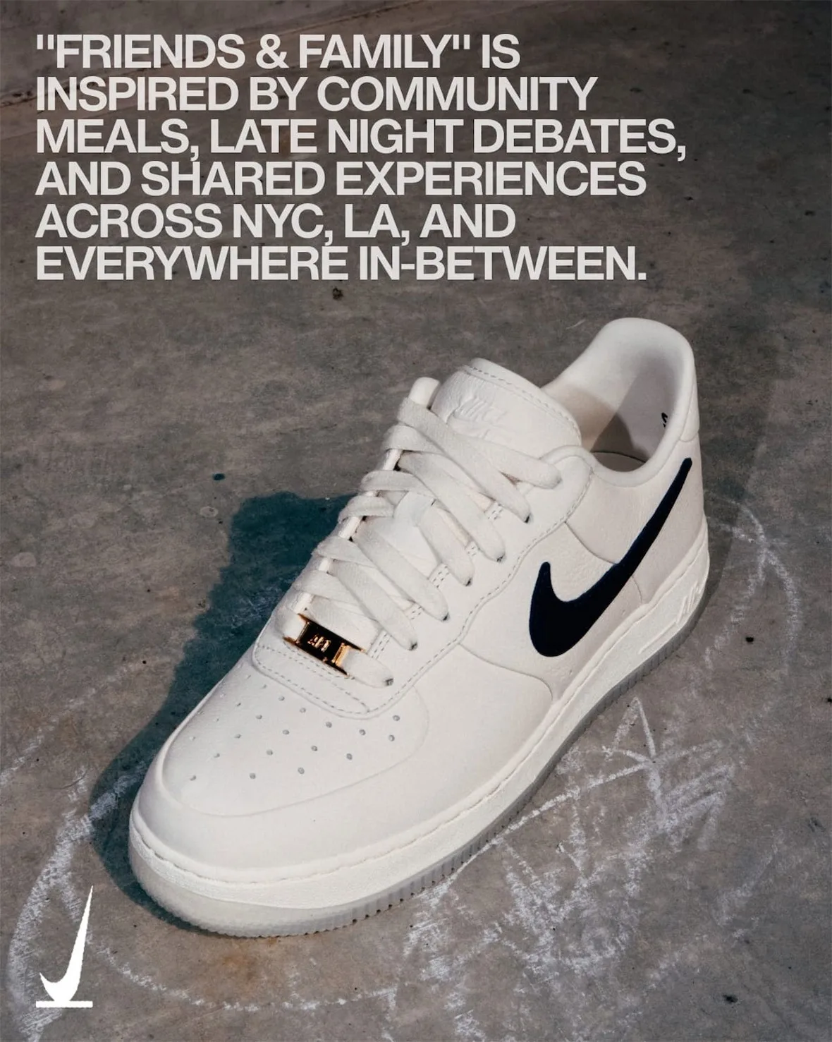 Lateral view on chalk-marked concrete, cream leather, navy swoosh, gold lace tag, grey translucent sole, SNKRS Friends &