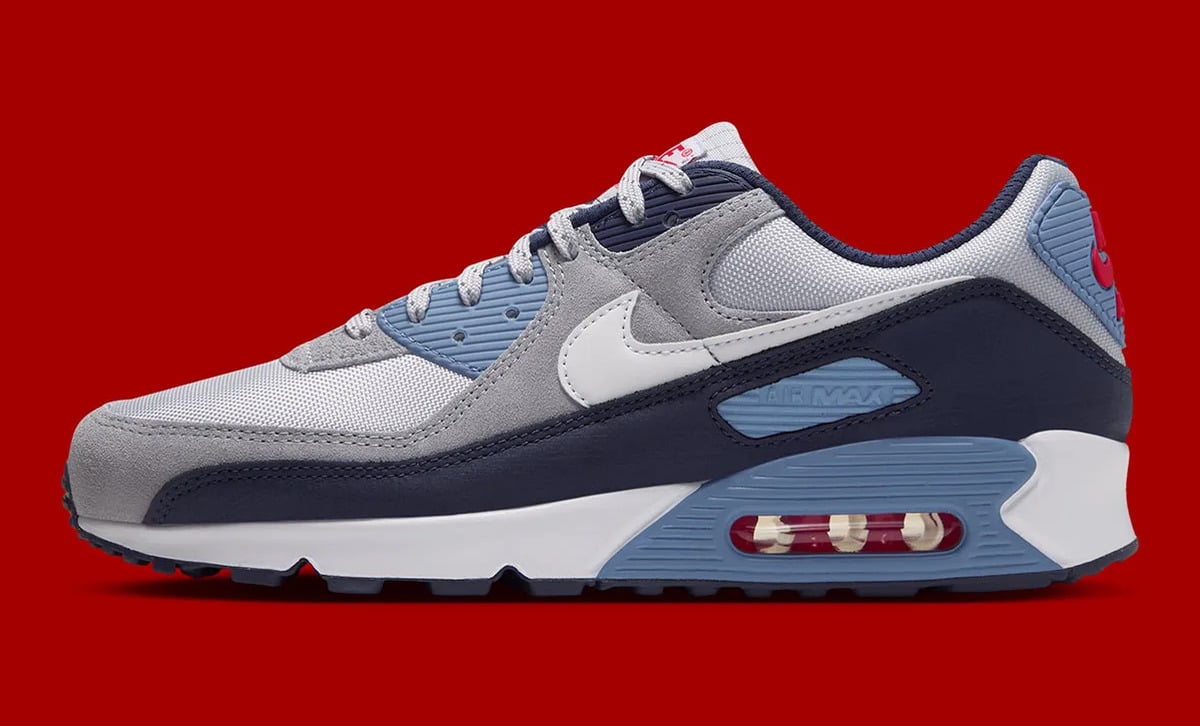 Lateral view, grey suede and navy overlay, light blue heel Air unit, red backdrop, Geyser Grey