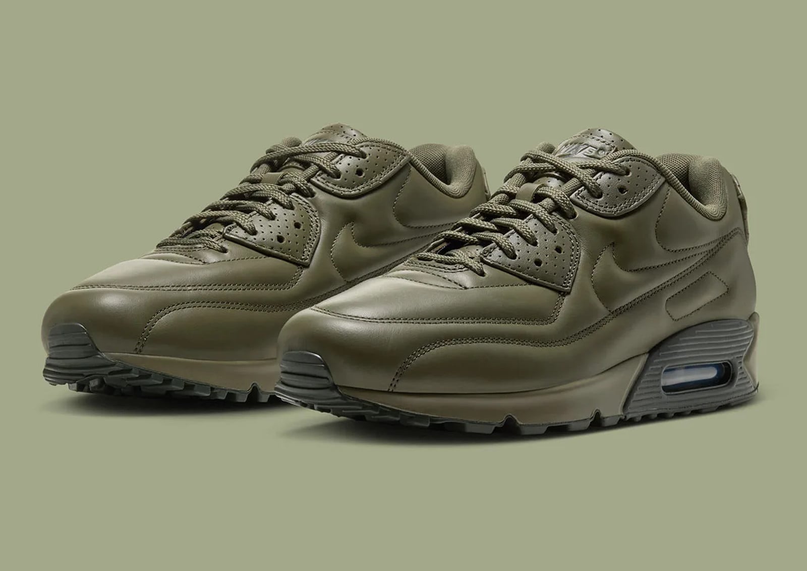 Pair in three-quarter view, olive leather uppers with tonal swooshes on a green backdrop, Nike Air Max 90 SP “Medium Olive”