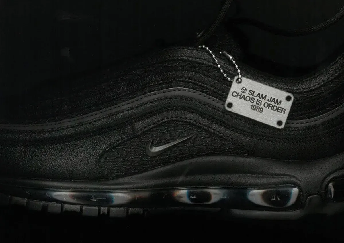 Lateral detail of black textured upper with tonal swoosh and silver Slam Jam dog tag, Nike Air Max 97 x Slam Jam “Black”