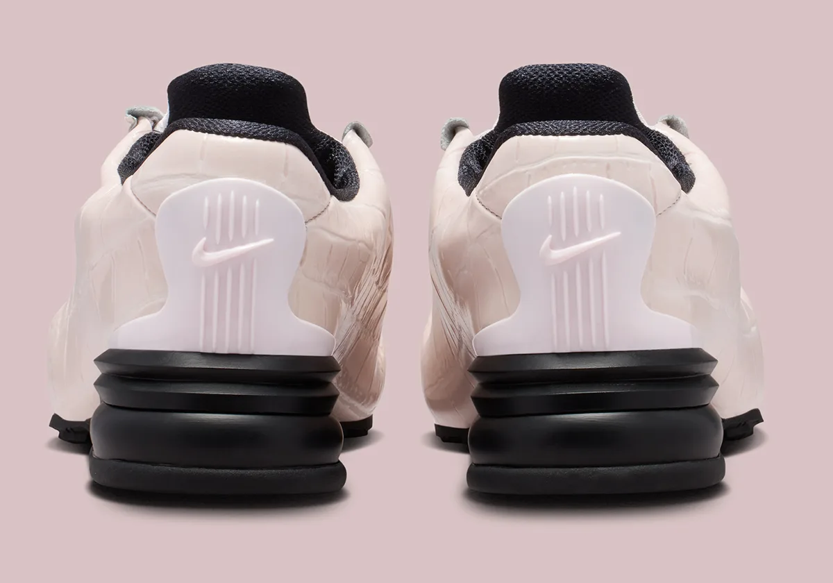 Heel view of pair, pale pink croc leather, white heel clip with Swoosh, pink backdrop, Pearl Pink