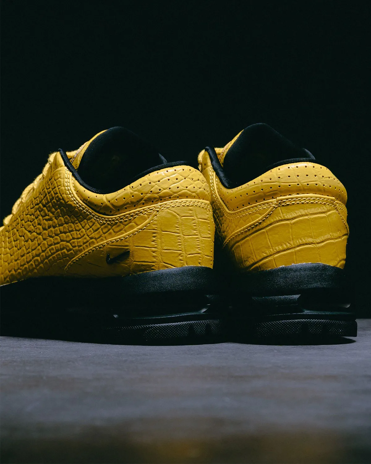 Heel view of pair in yellow croc-embossed leather with perforations, black swoosh and black sole, Vivid Sulfur