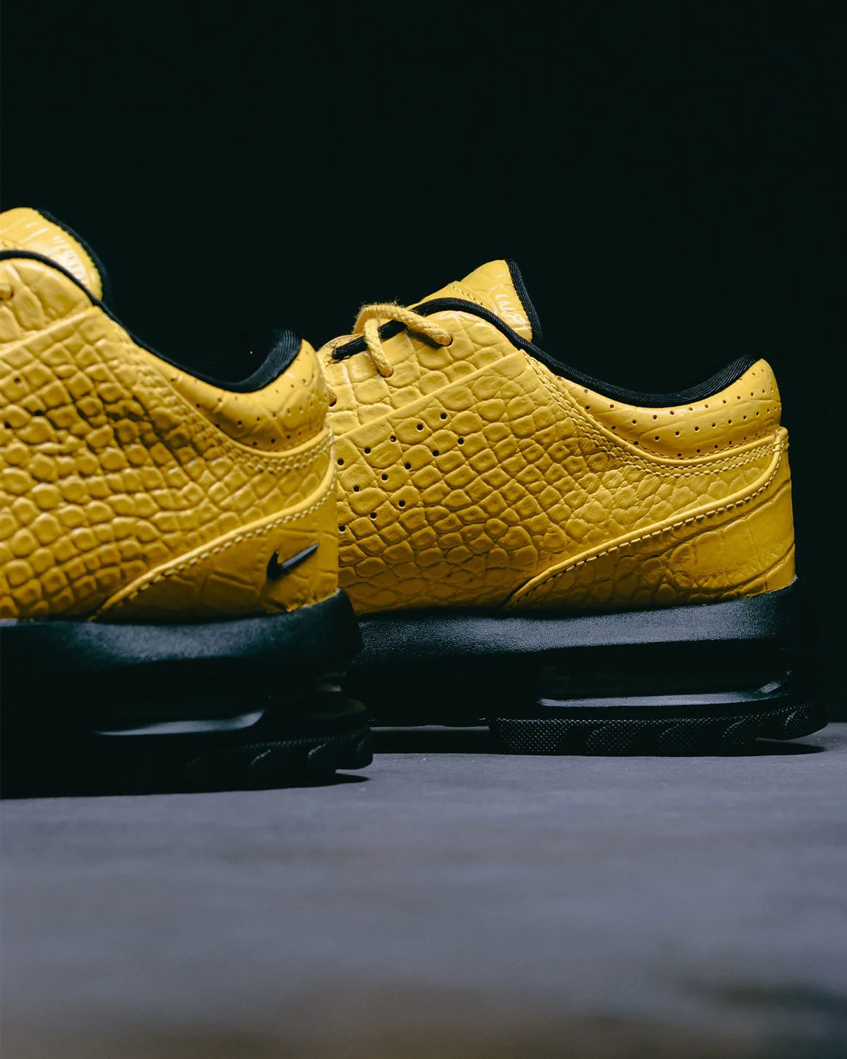 Low-angle heel and lateral detail of yellow croc-embossed leather, small black swoosh, black sole, Vivid Sulfur