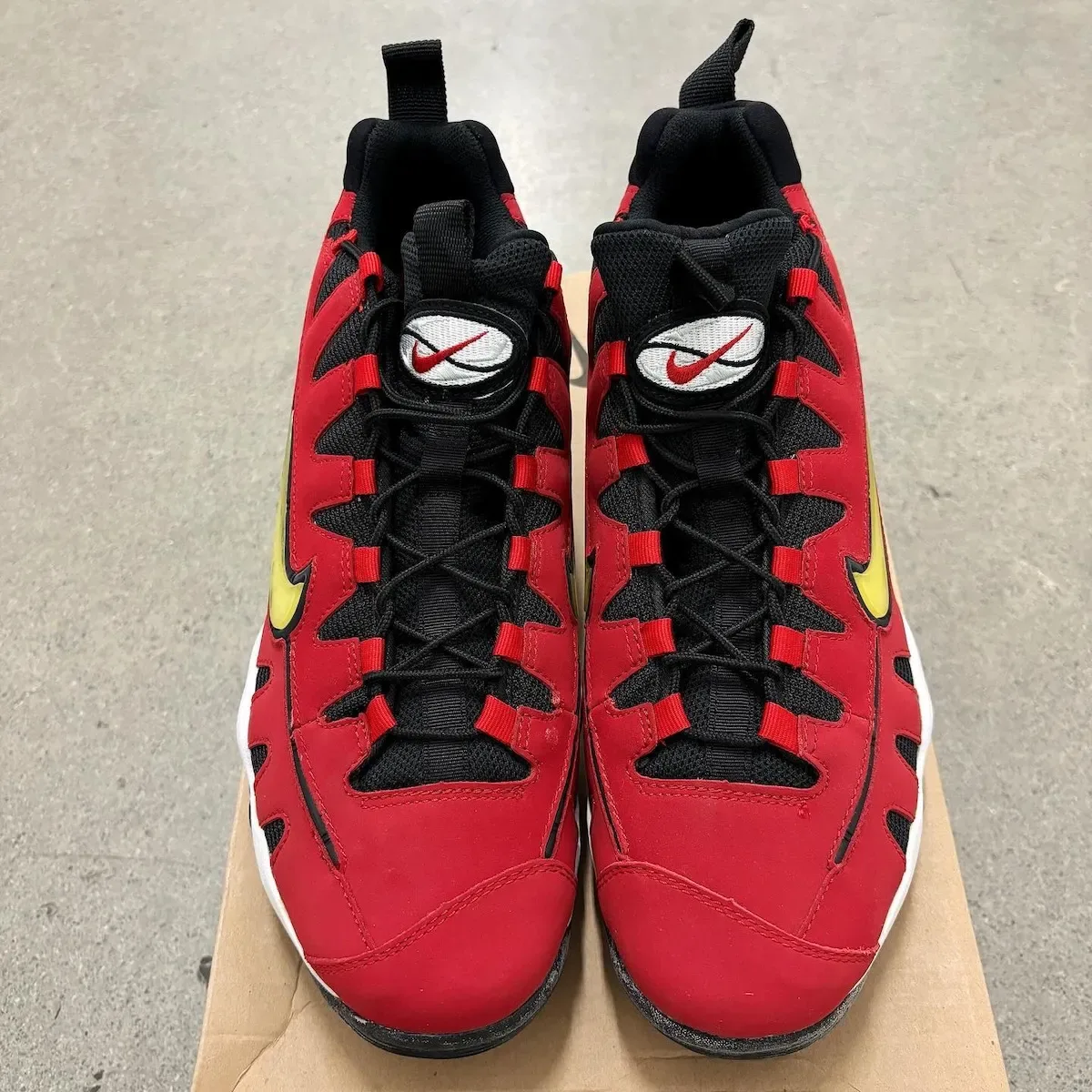 Top-down view of pair, black laces, red eyelet loops, white tongue badge, yellow swoosh edge, Varsity Red