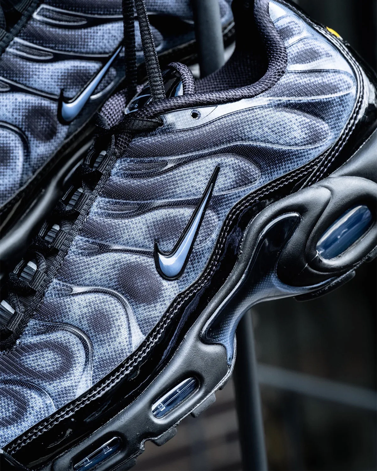 Lateral detail of light blue-grey swoosh on mottled mesh, black patent trim, blue air windows, Black/Cool Grey