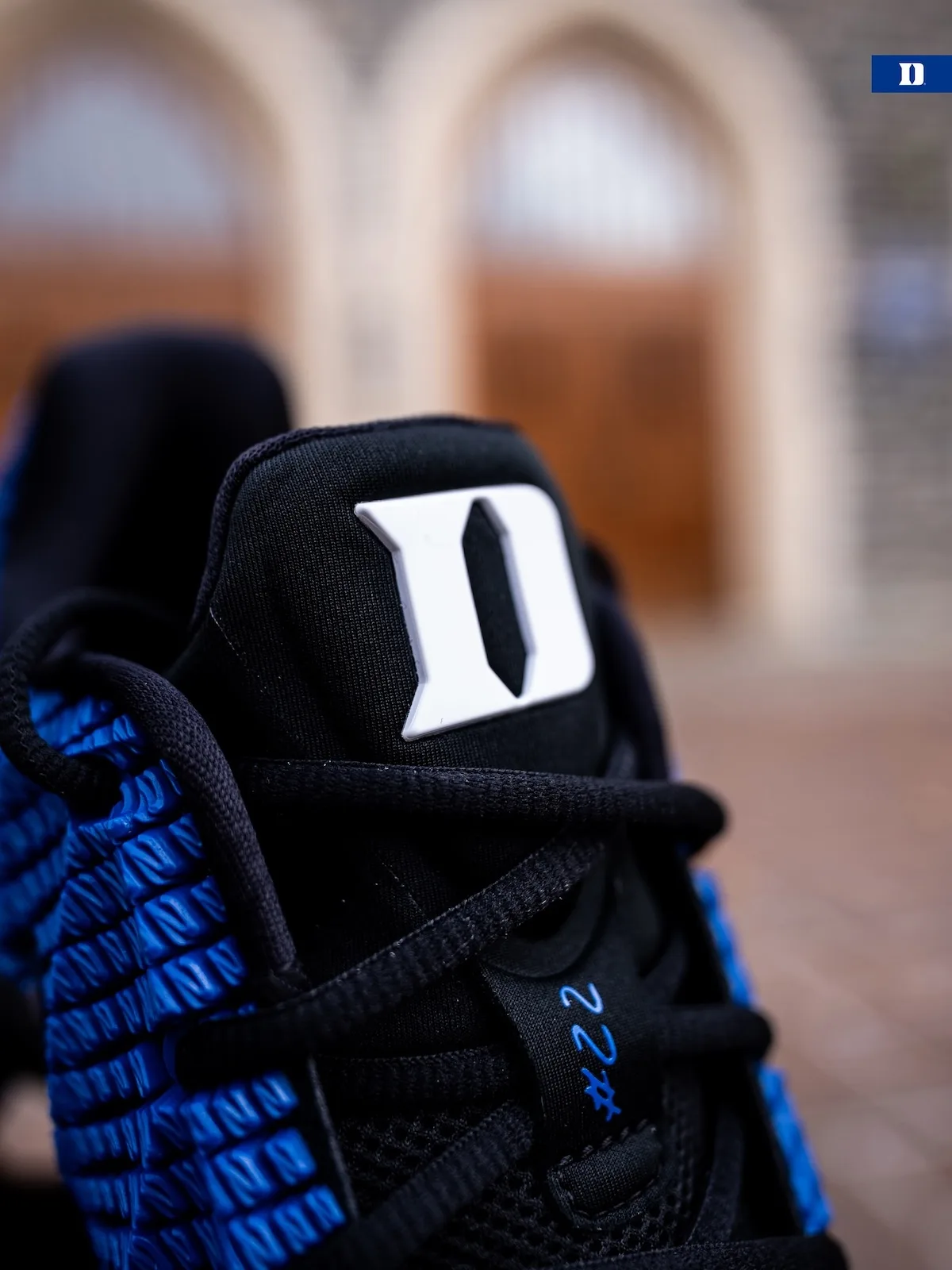 Close detail of black tongue with white Duke D and blue #22 lace tag, blurred arches, Duke