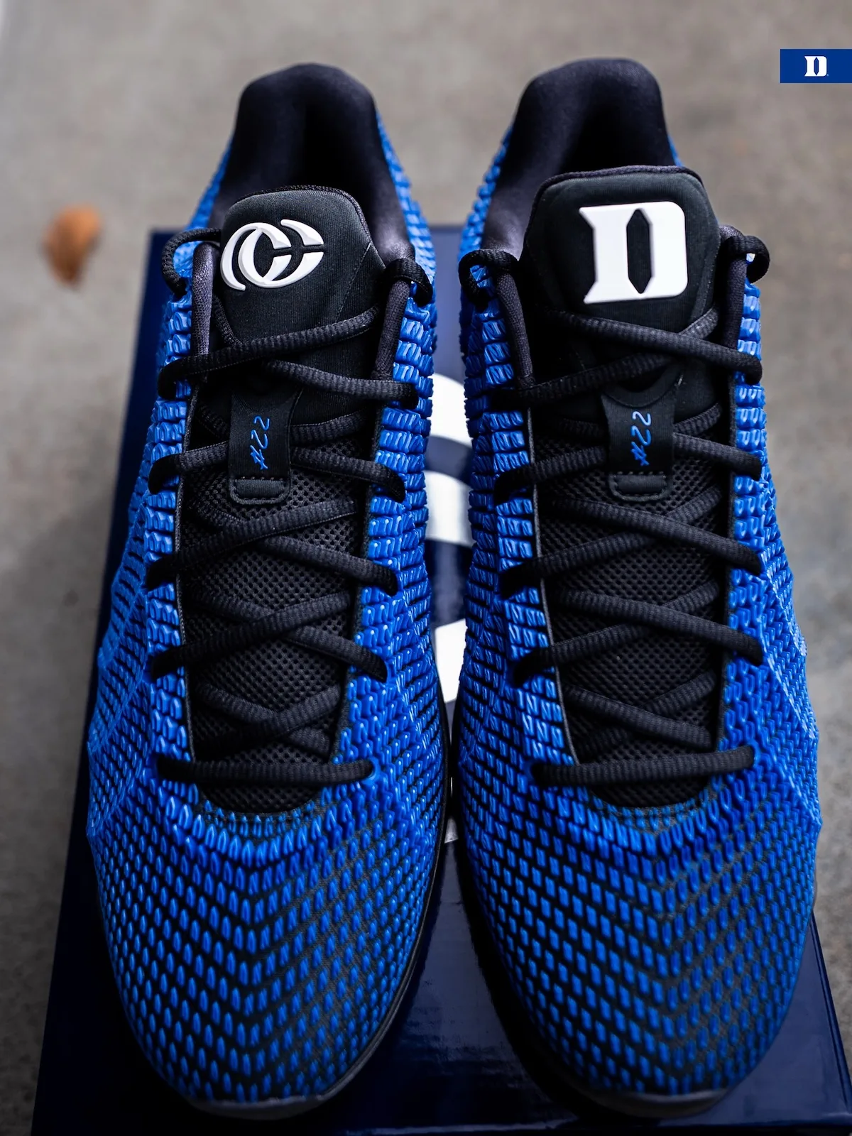 Top-down pair on blue box, white Duke D and logo on black tongues, #22 lace tags, Duke