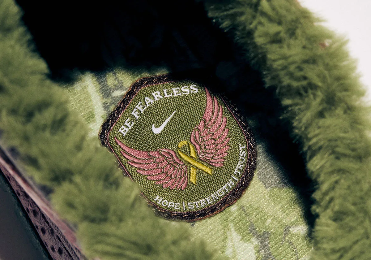 Detail of a green embroidered patch reading Be Fearless with pink wings, on green fleece, Freestyle 2027 Collection