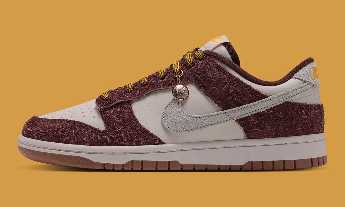 Lateral view with a gold basketball charm on the laces, grey swoosh, on a mustard background, Basketball Charm