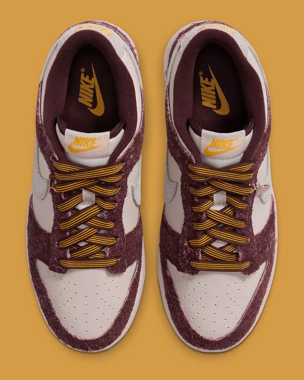 Top-down view of a pair, striped gold and burgundy laces, gold Nike logos on insoles and tongues, Basketball Charm