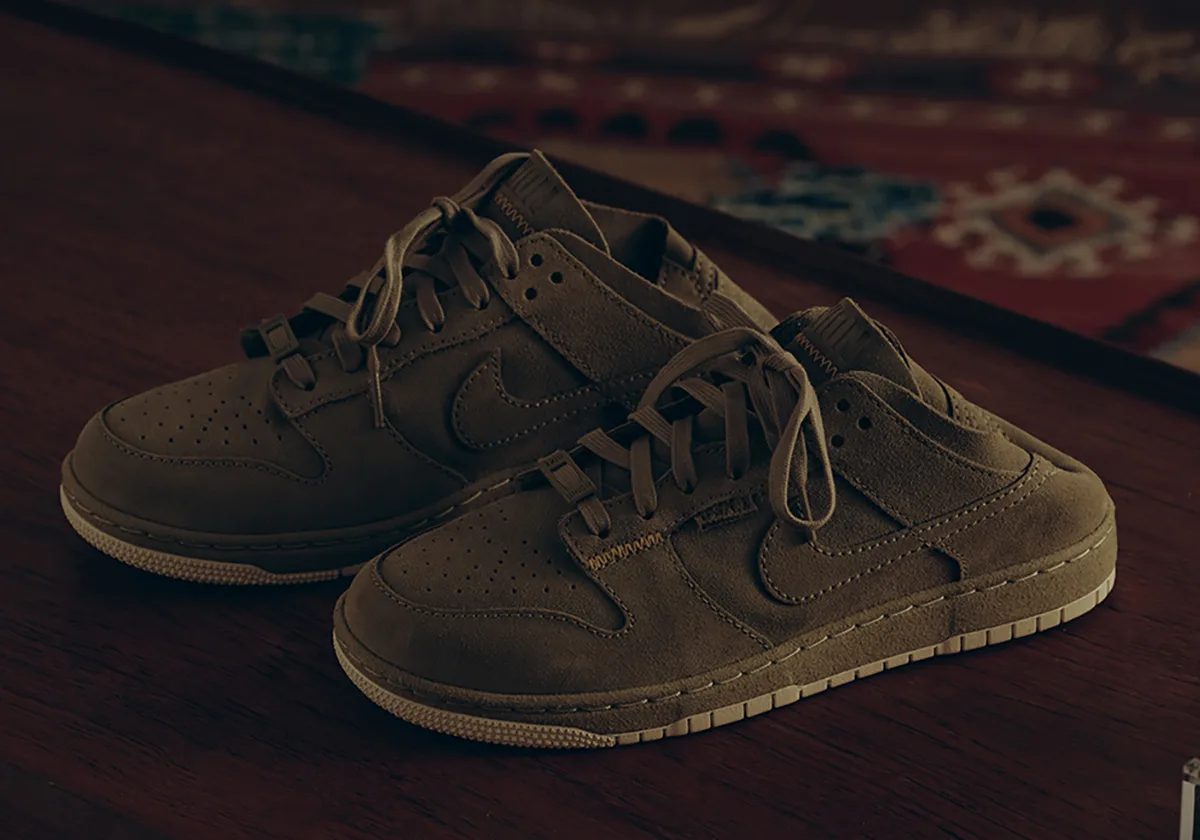 Pair of olive suede backless low-tops, tonal laces, cream sole, on dark wood table, Natural Selection