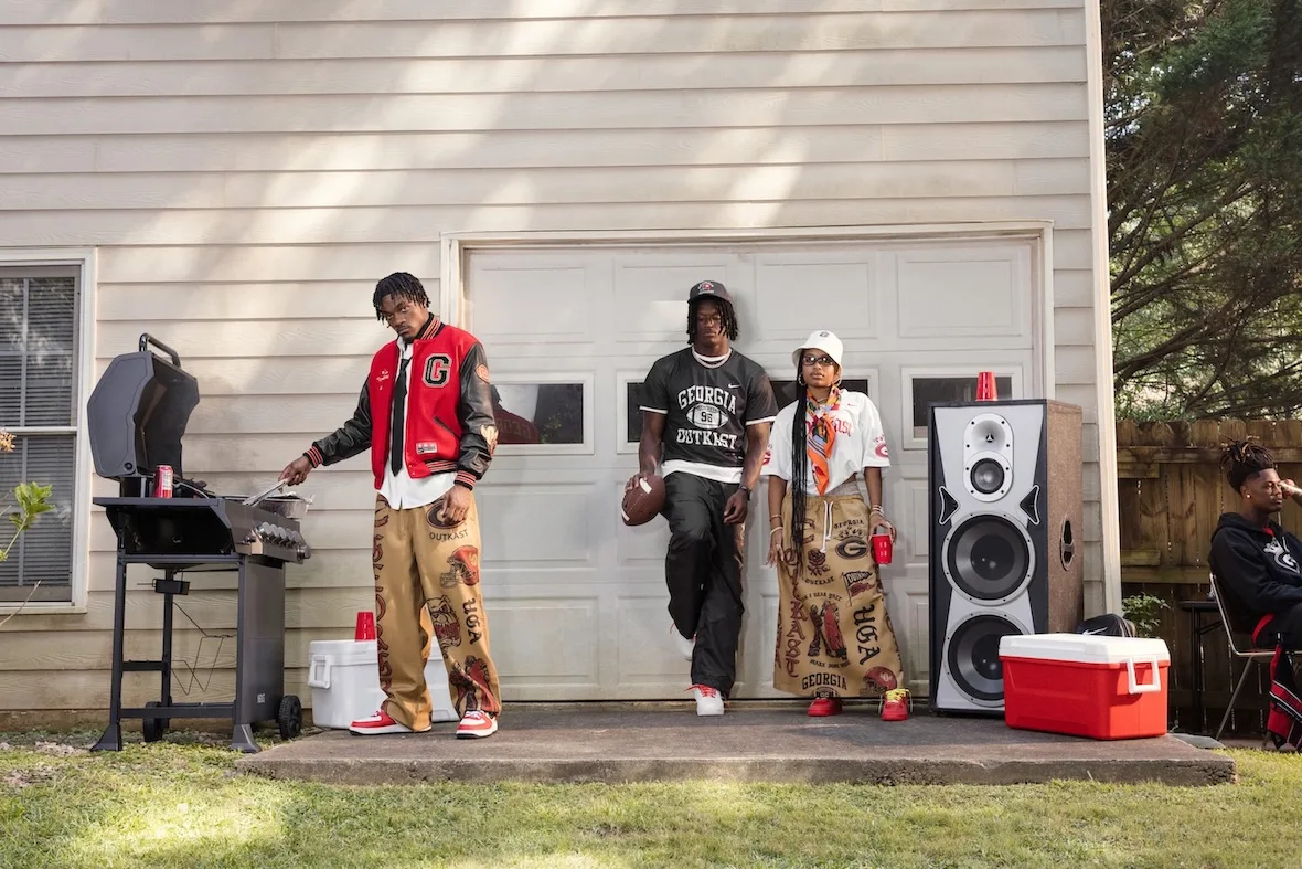 Three people outside a garage with grill, speaker and red cooler, Georgia Outkast clothing, Outkast Football Collection