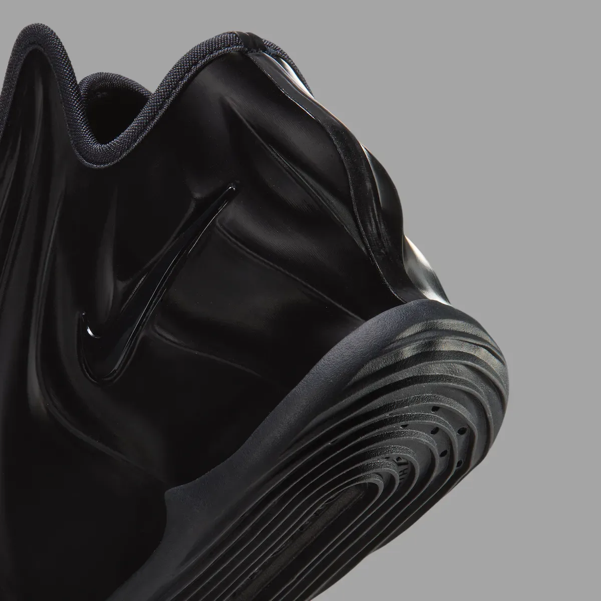 close-up of pleated toe box and ridged outsole, black swoosh, grey background, Triple Black