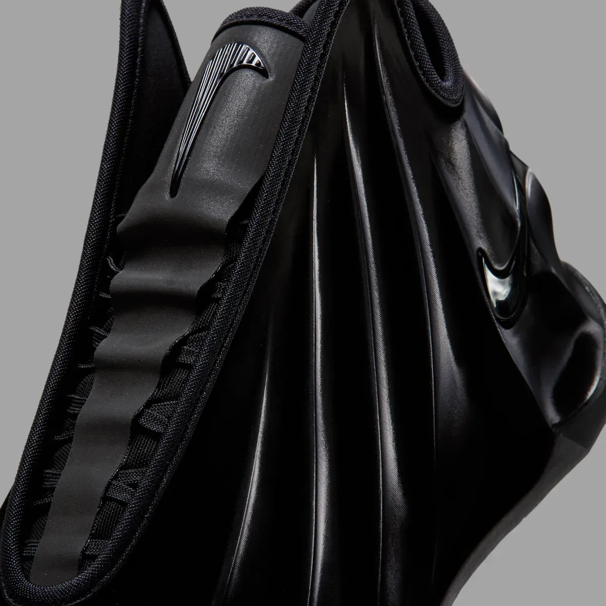 close-up of collar and draped upper above ridged outsole, grey background, Triple Black