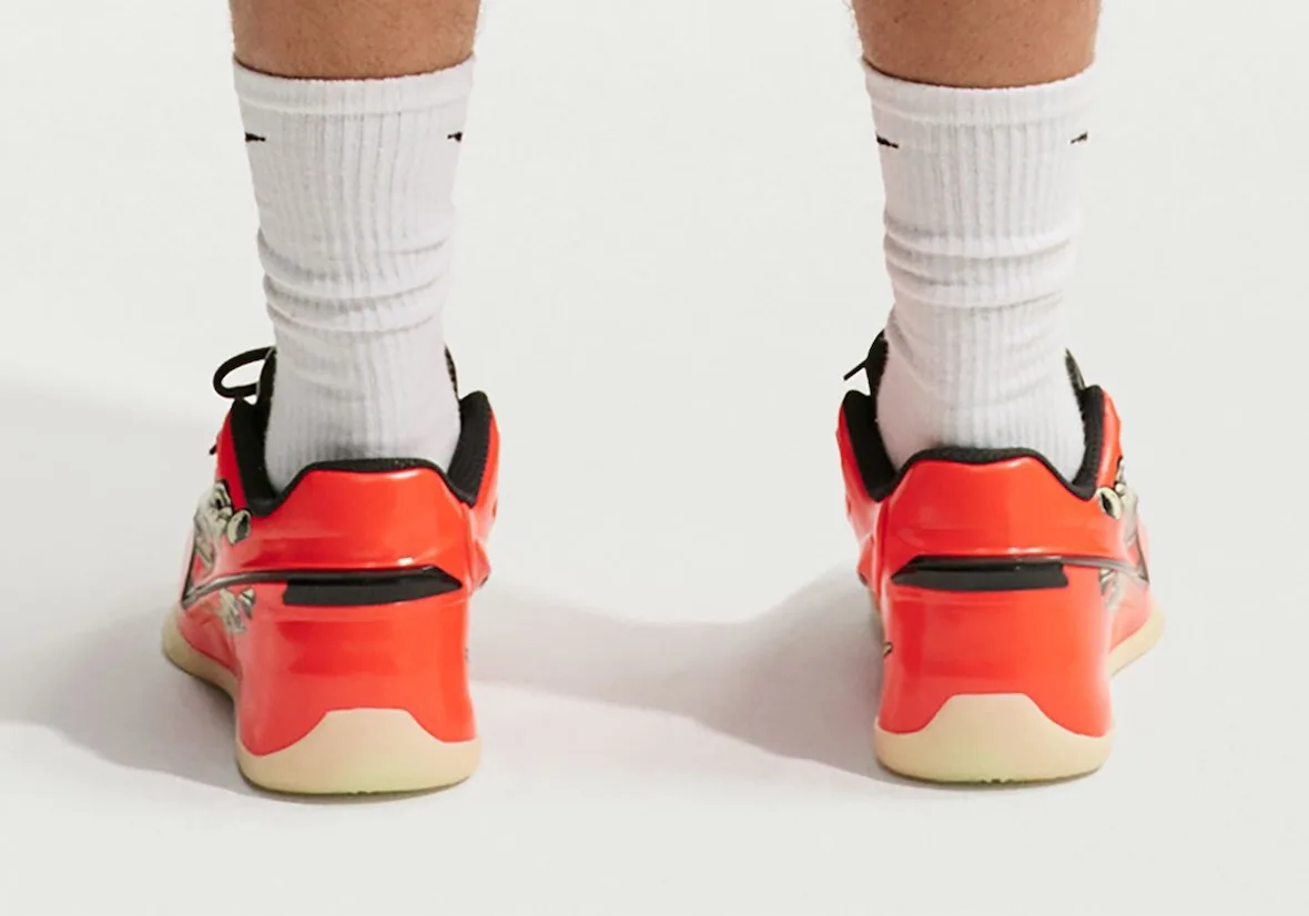 On-foot heel view of glossy orange shoes with black trim and cream soles, Halloween