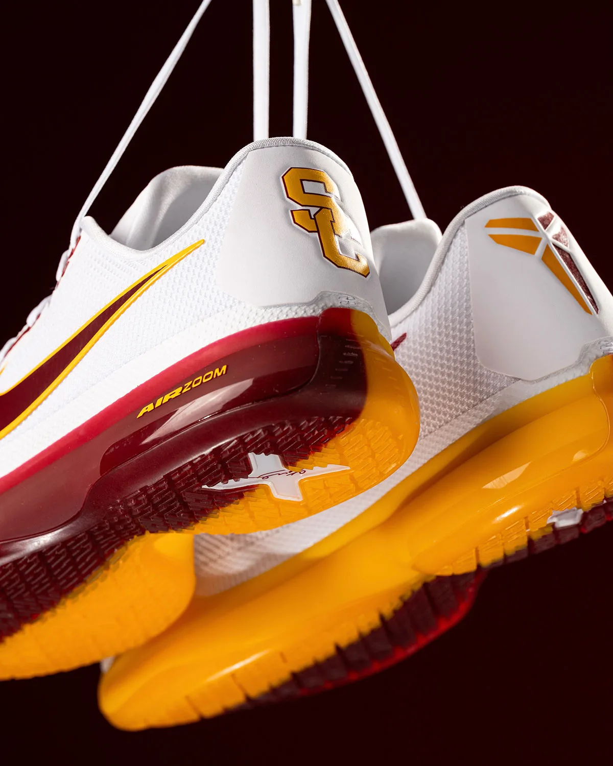 Detail of white pair's heels with gold SC logo, Air Zoom text, gold outsoles, USC