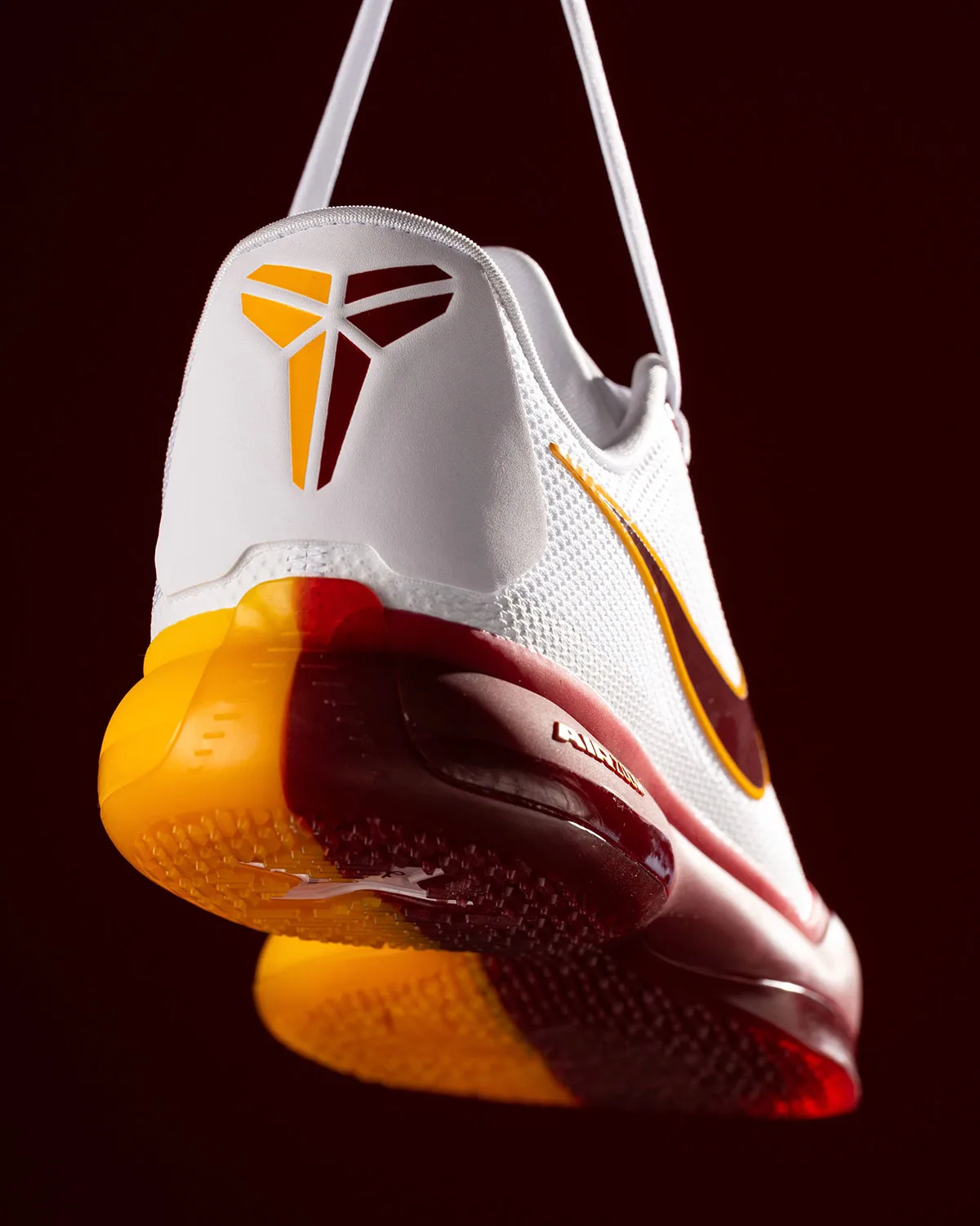 Heel view of white shoe with gold and maroon logo, gold and maroon sole, USC