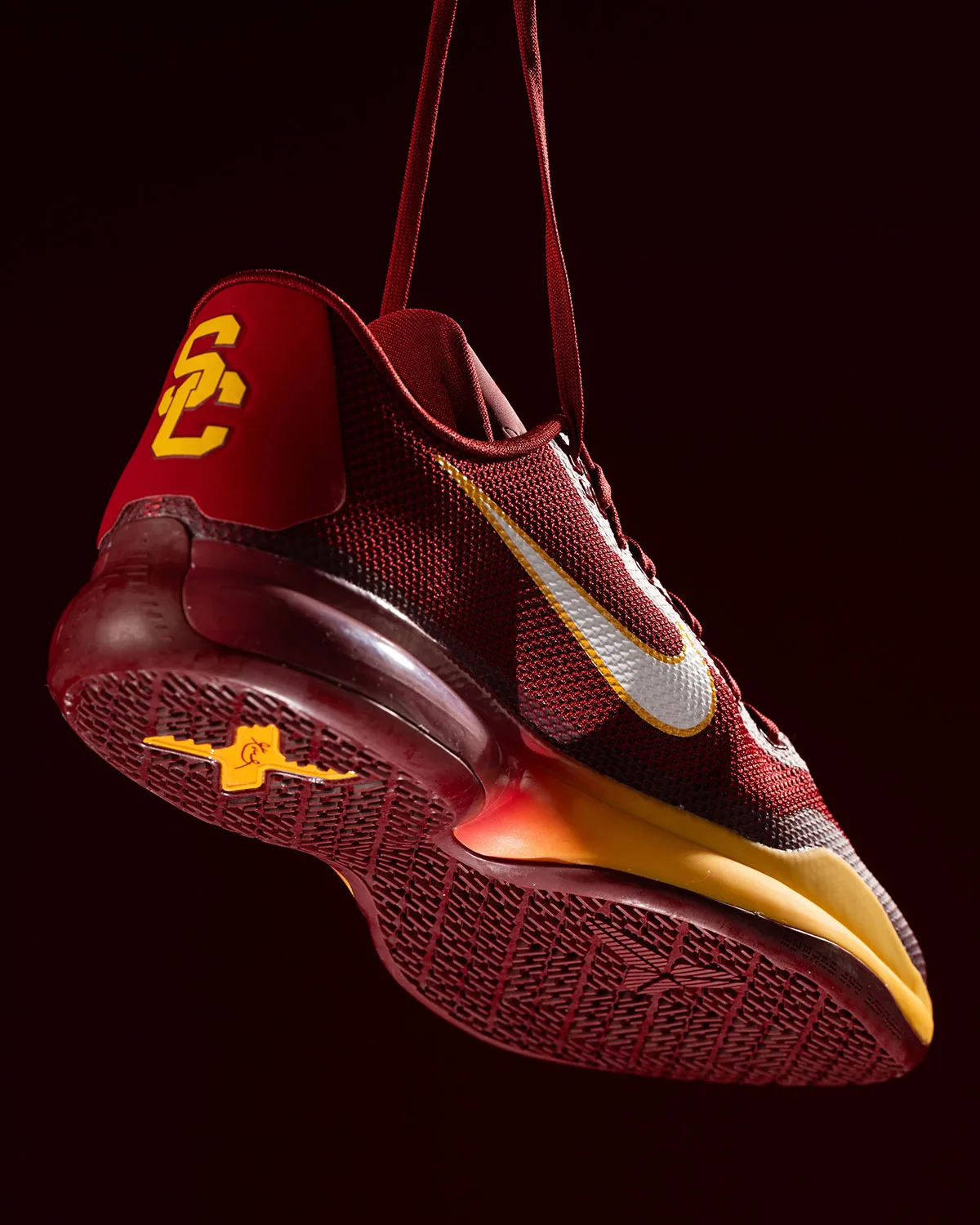 Red shoe tilted showing outsole, gold SC heel logo, white swoosh and gold tip, USC