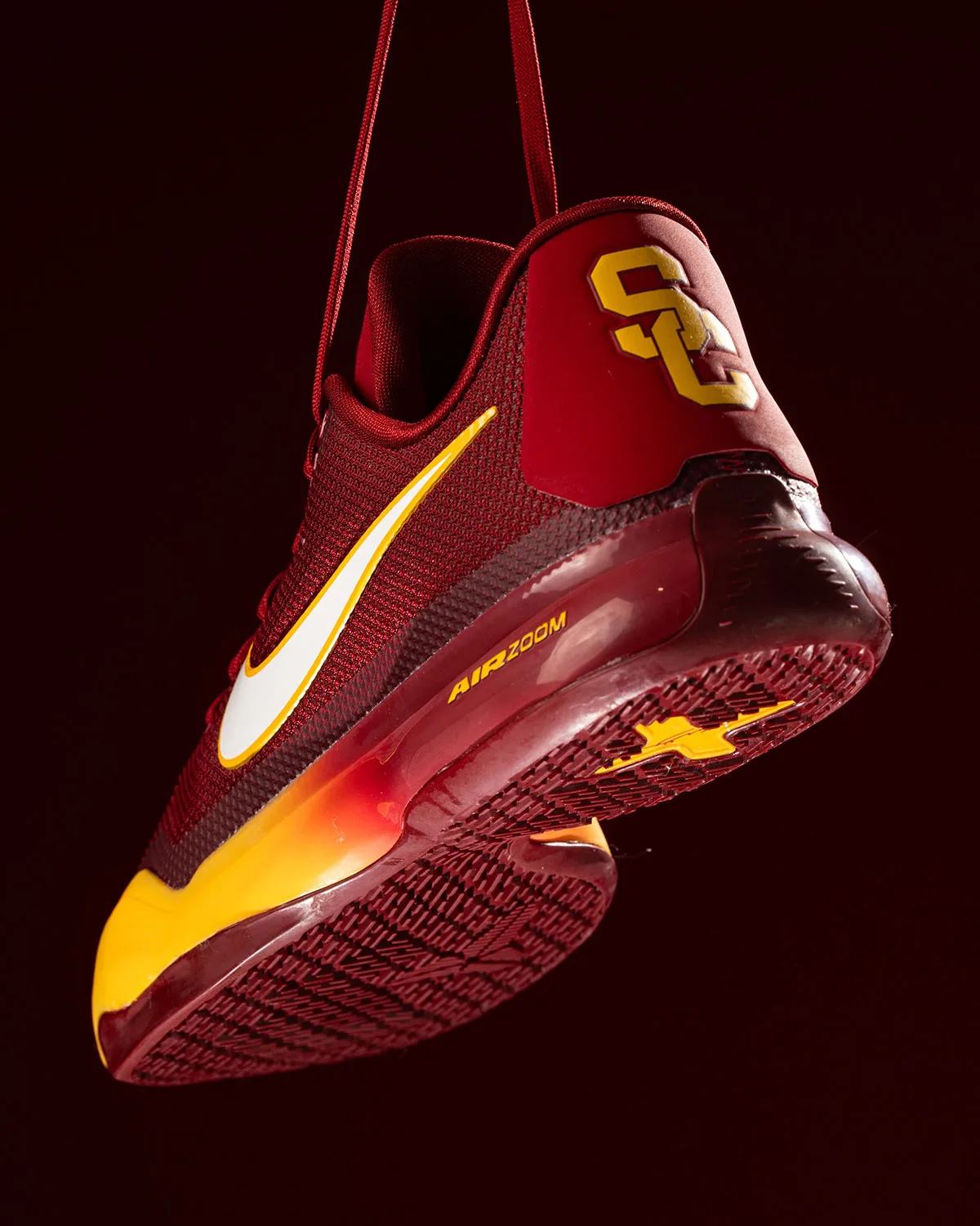 Heel and outsole view of red shoe with gold SC logo and white swoosh, USC