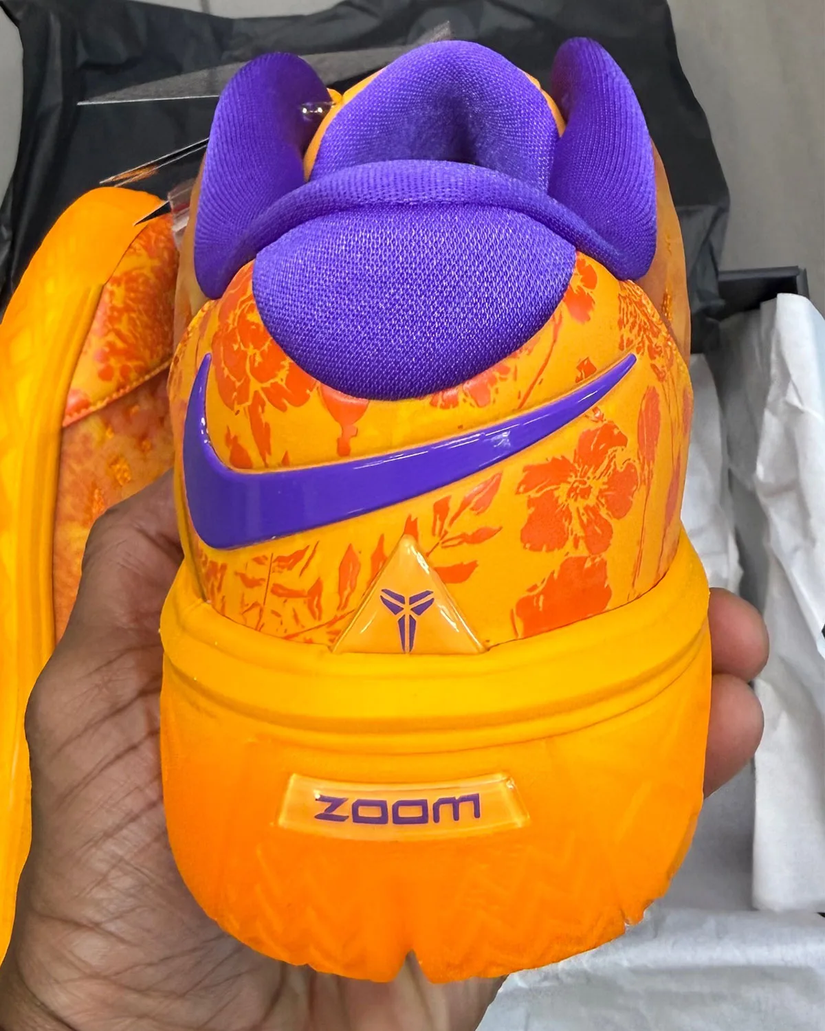 Heel view in hand: purple swoosh, purple collar, triangular logo, Zoom window on orange midsole, Mamba Eterno