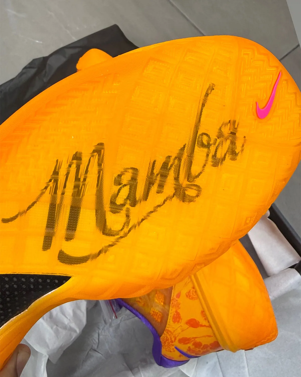 Outsole in hand: translucent orange rubber with a Mamba script signature and a pink swoosh, Mamba Eterno