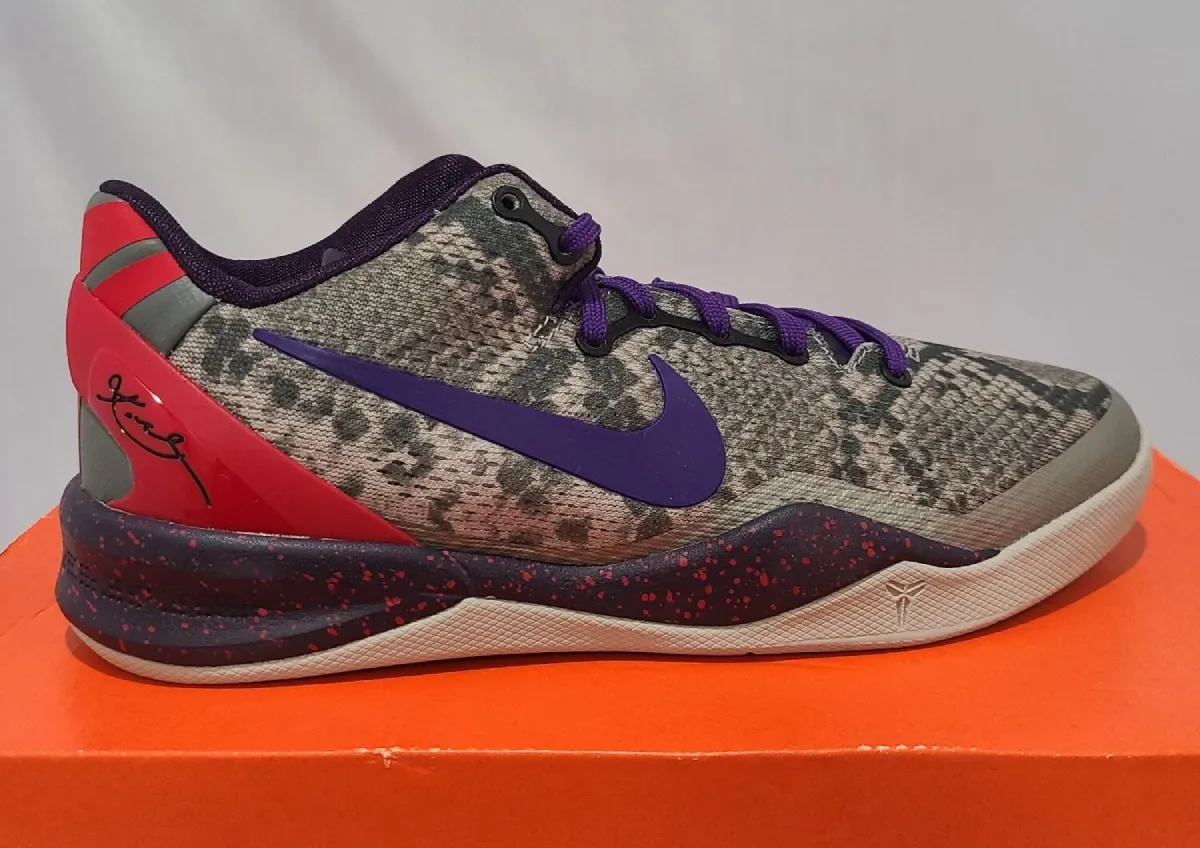 Lateral view on an orange shoebox, purple swoosh, red heel clip and speckled midsole, Mine Grey