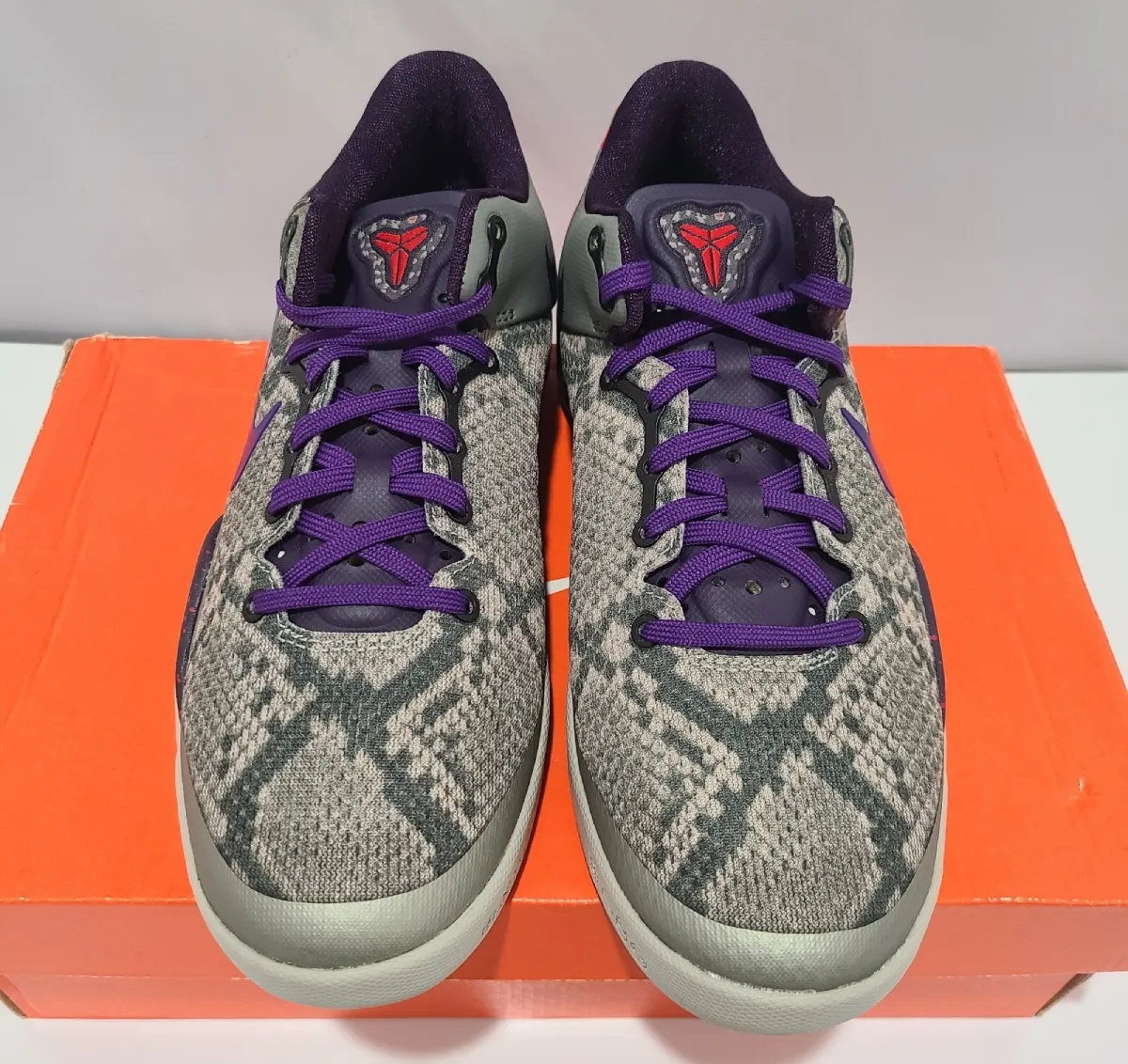 Top-down view of pair on orange shoebox, purple laces, grey snakeskin-print toe boxes, Mine Grey