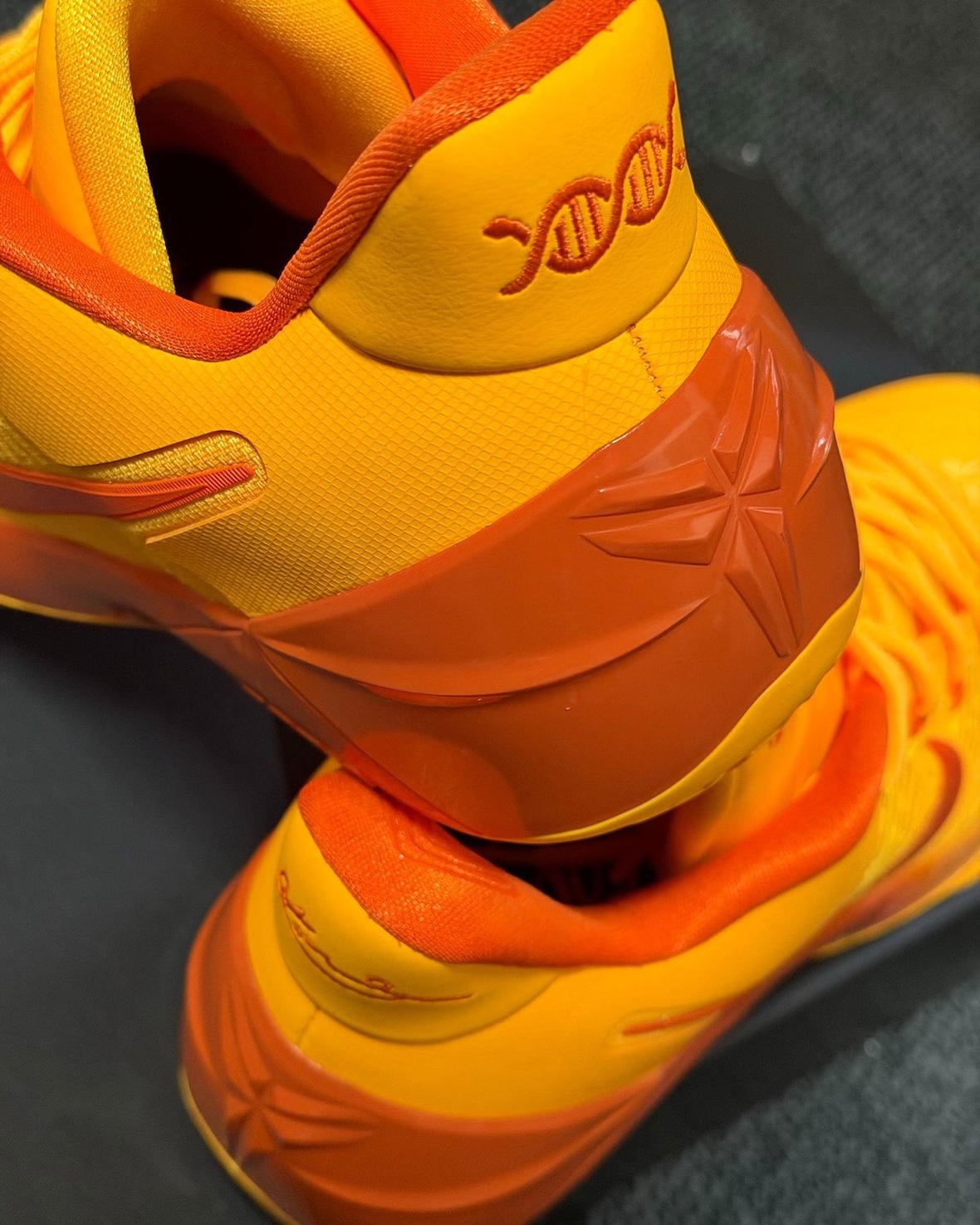 close-up of heel showing embroidered DNA logo and Kobe sheath logo on orange counter, Laser Orange