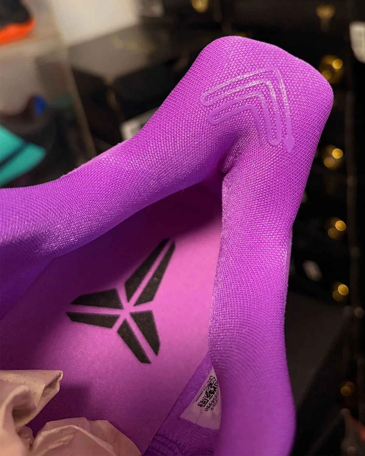 Close-up of purple heel with swoosh outline above pink insole and Kobe logo, Purple Stardust