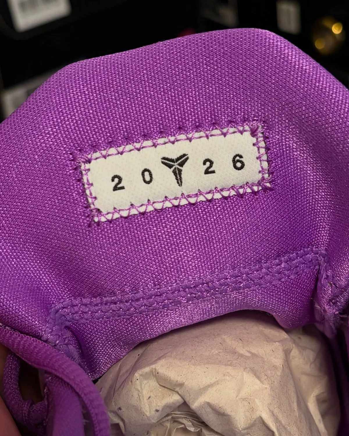Close-up of woven tag reading 2026 with mamba icon on purple tongue, Purple Stardust