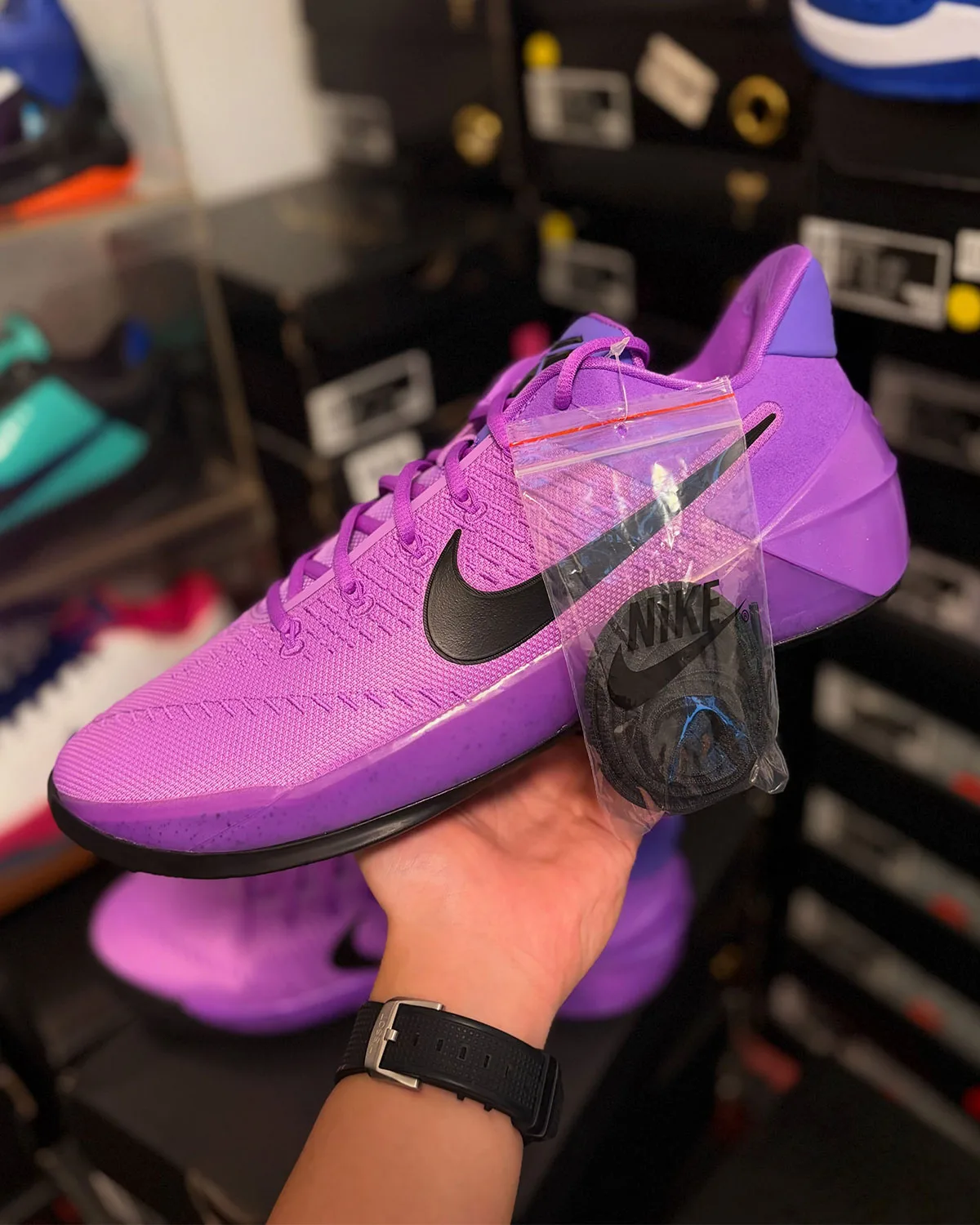 Lateral view in hand, purple upper with Nike hang tag still attached in plastic, Purple Stardust