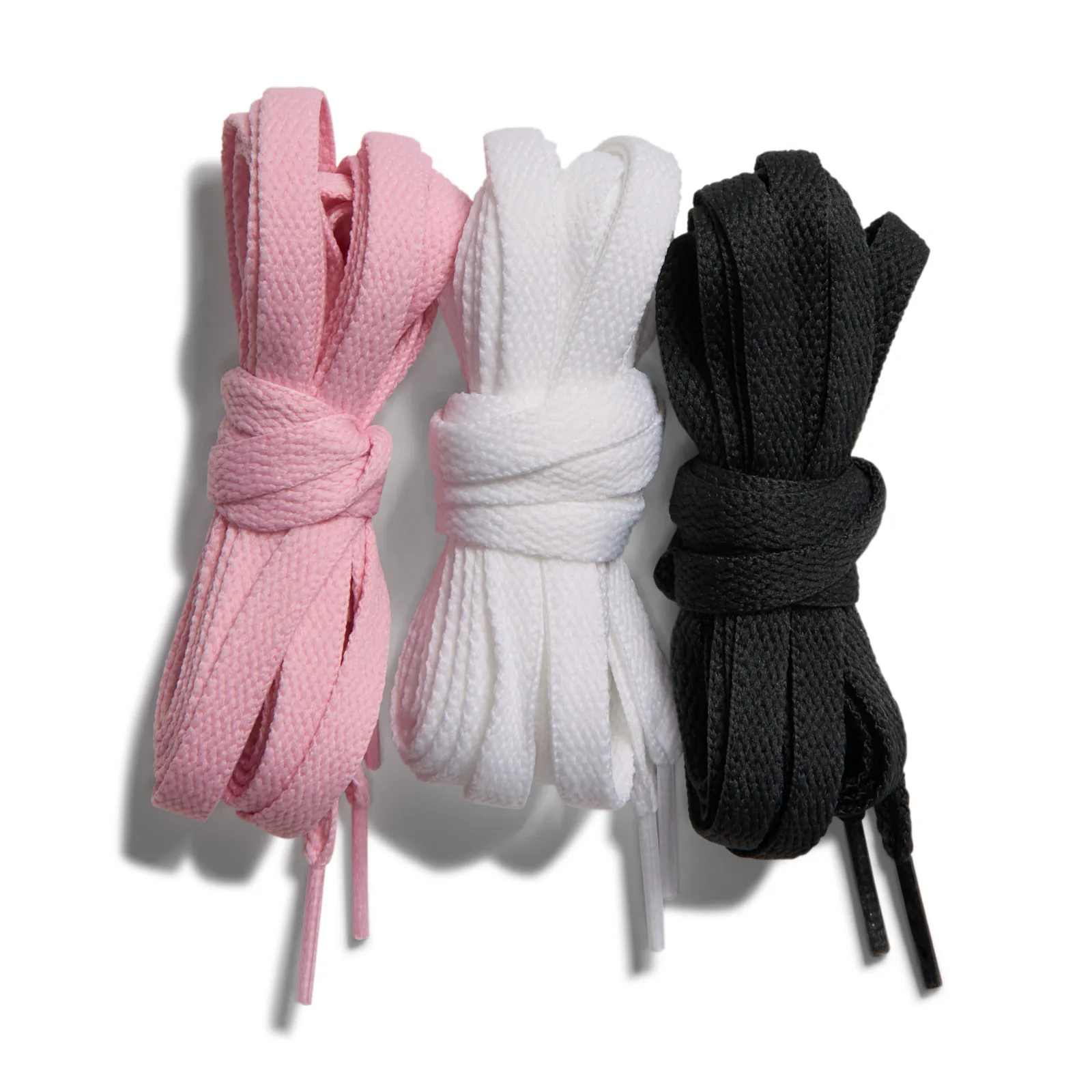Three bundles of flat laces, pink, white and black, tied up on a white background, Mamba Eterno