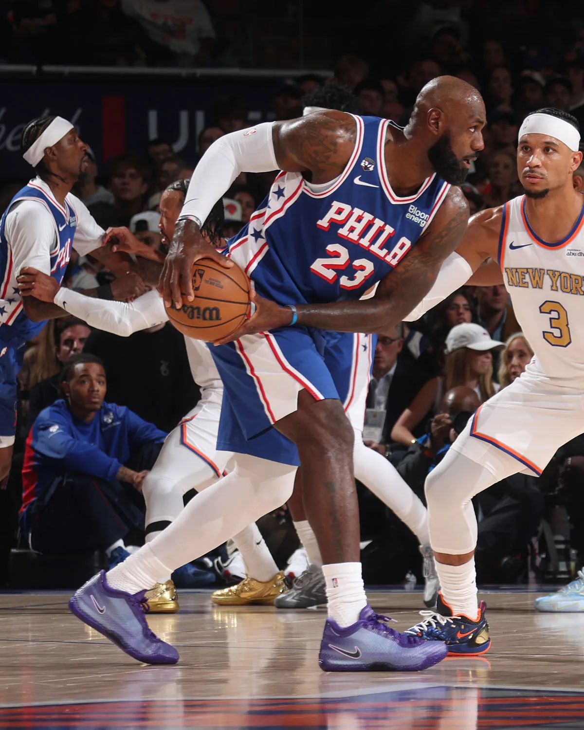 Player in blue Phila 23 jersey holding ball, purple sneakers, defender in white New York jersey, Opening Night