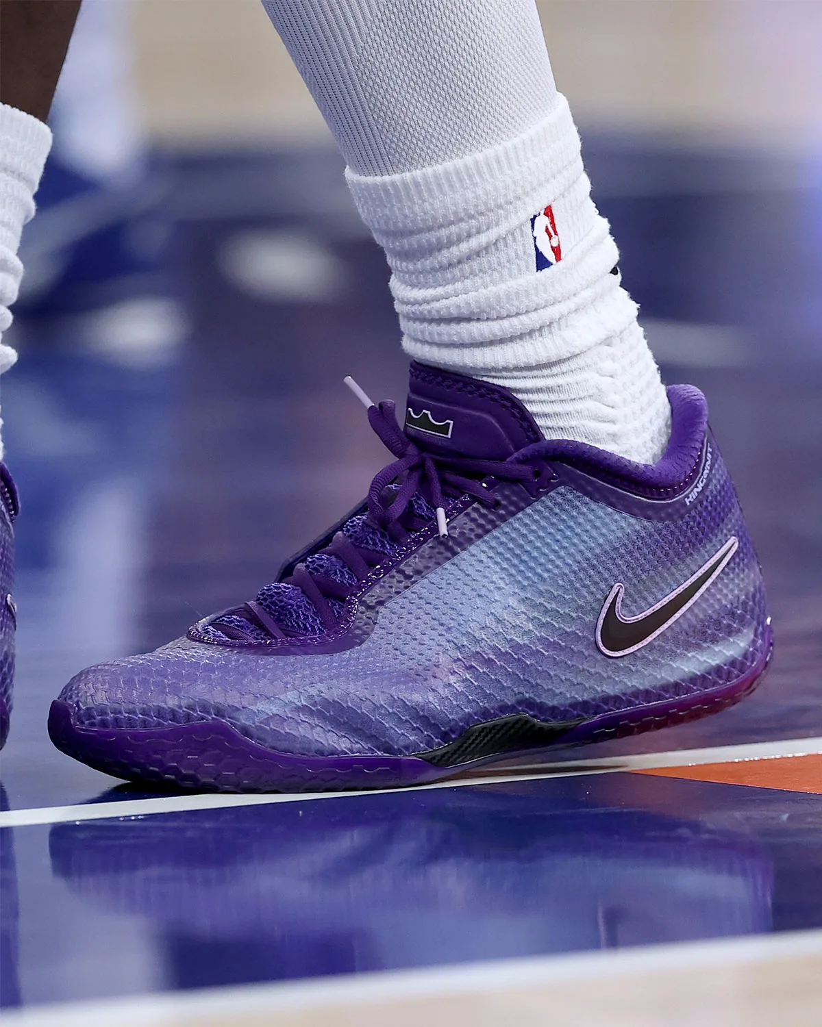 Close on-foot lateral view of purple sneaker with black swoosh, white NBA sock, court lines, Opening Night