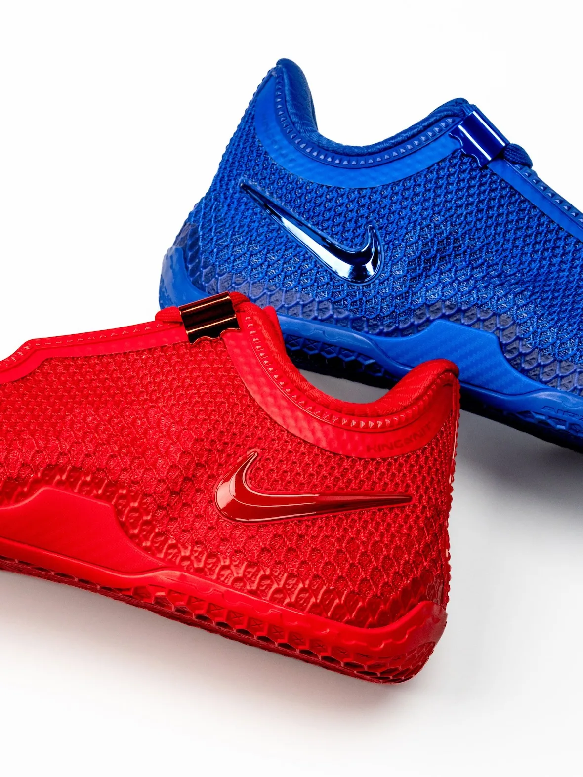 Detail of red and blue pair on white, glossy swooshes, textured mesh and metallic lace clip, Philly