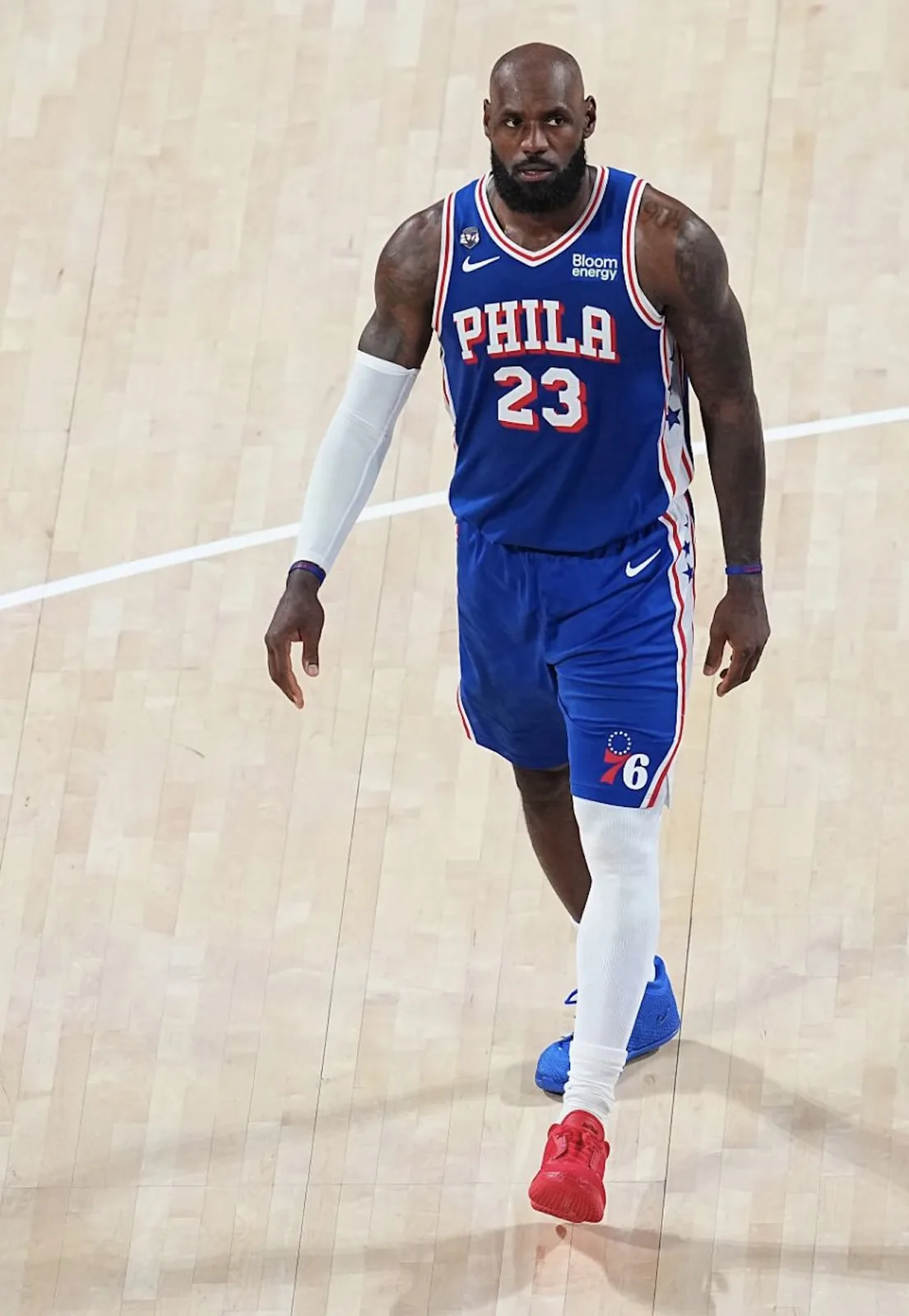 On-court full-body view of player in blue Phila 23 jersey, one blue and one red shoe, Philly
