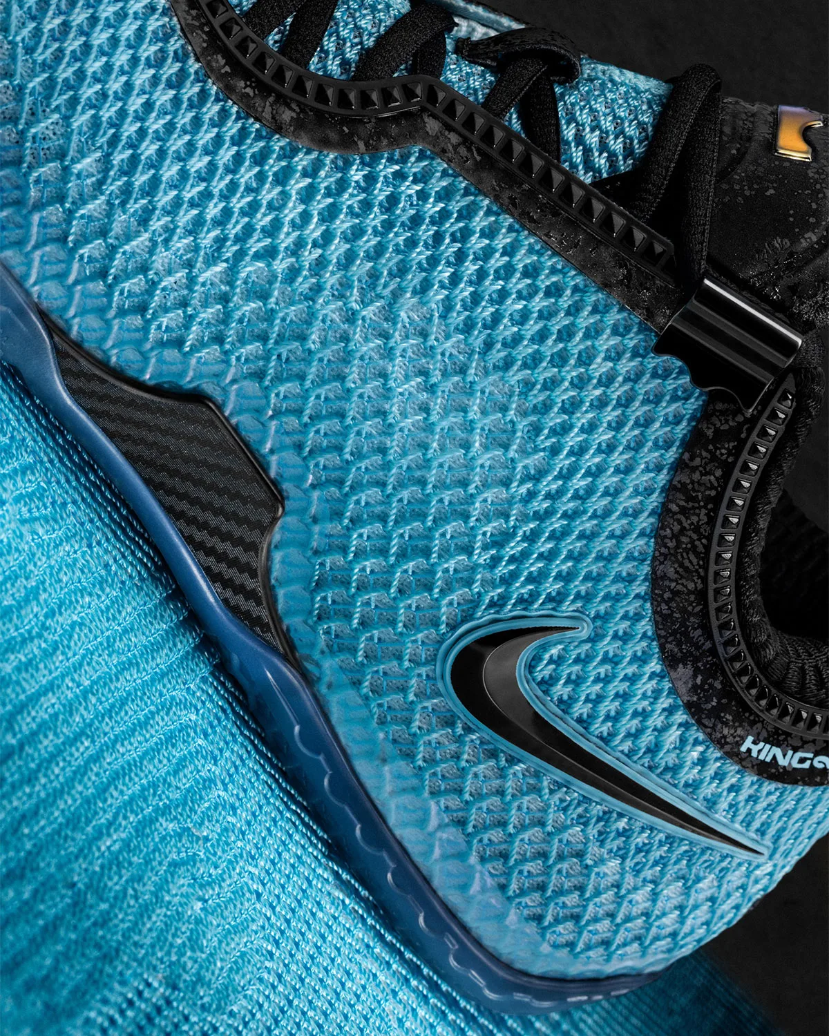 Detail of blue textured knit upper with black swoosh, carbon-look panel and lace clip, Stars