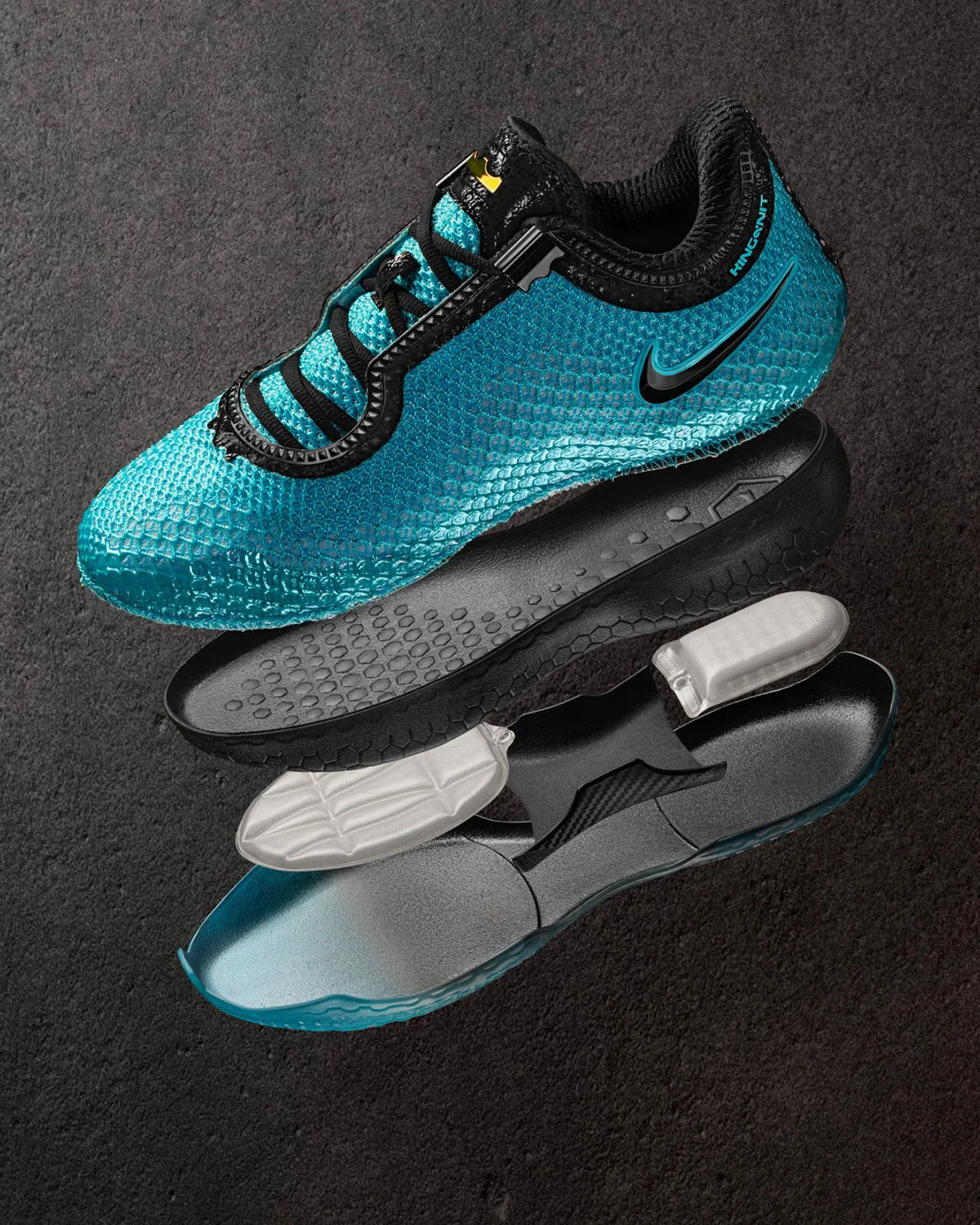 Exploded view of blue knit shoe with black midsole, white inserts and carbon plate on dark gravel surface, Stars
