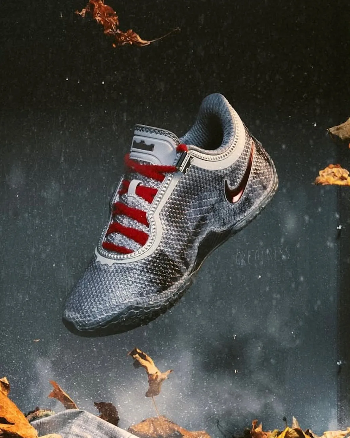 Shoe floating on a dark speckled backdrop with autumn leaves, red laces and chrome swoosh, Storm Drain