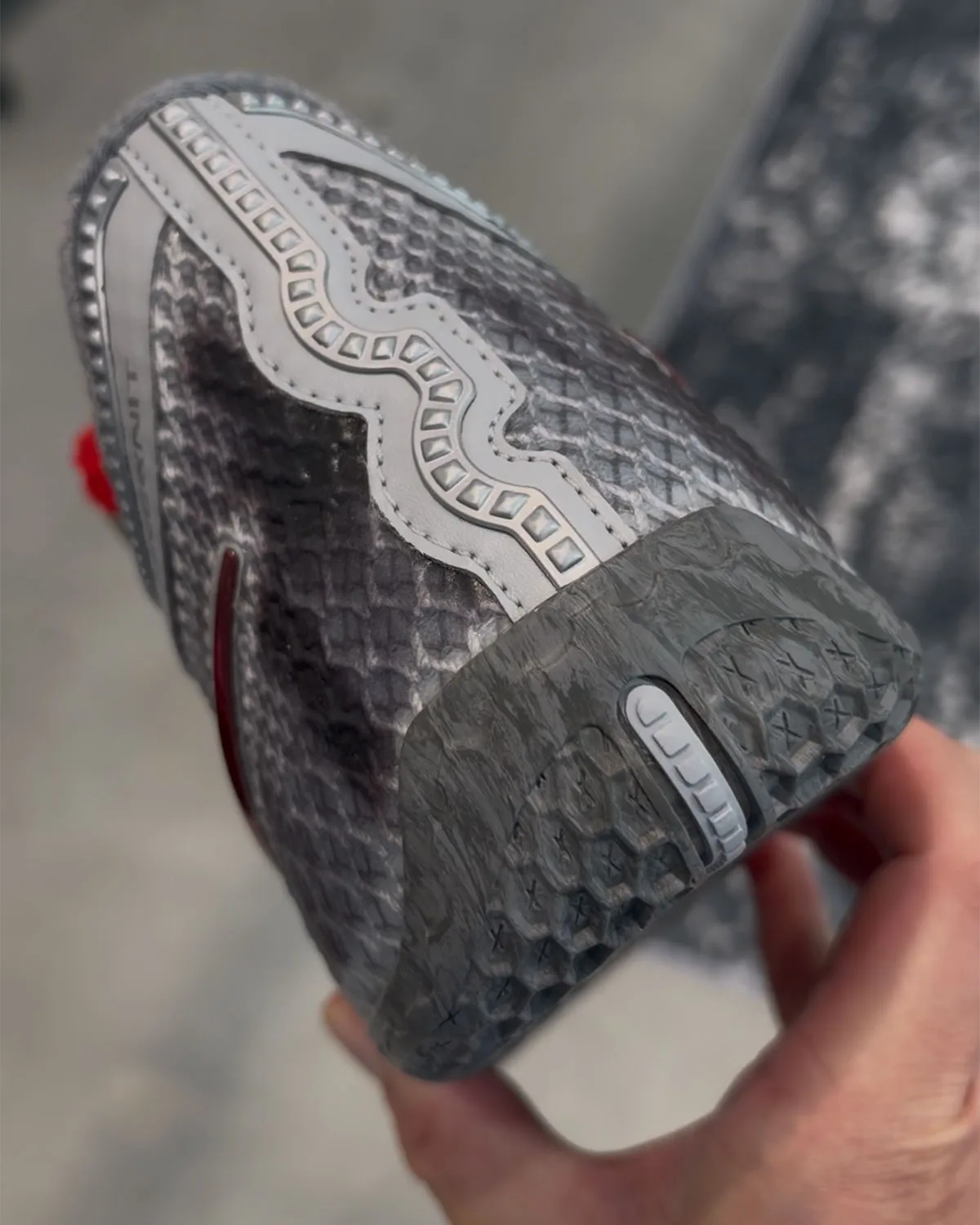 Heel and outsole detail held in hand, studded grey strip, grey rubber with X pattern, Storm Drain