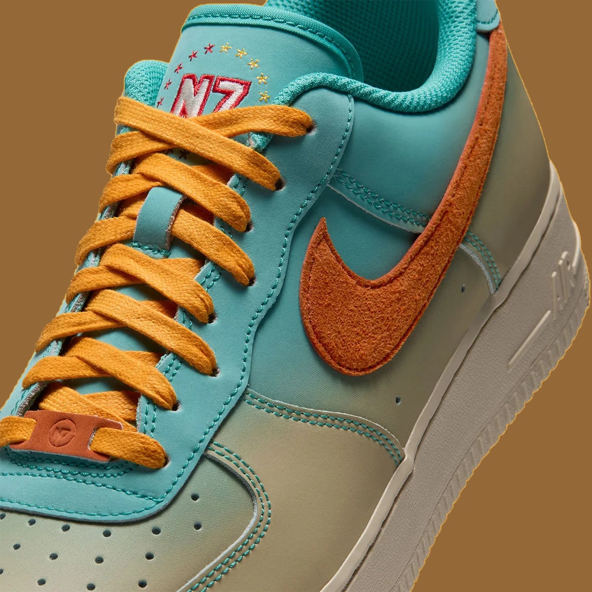 Close-up of laces and forefoot, N7 tongue embroidery, orange suede swoosh, small orange lace tag, Holiday 2026 Collection