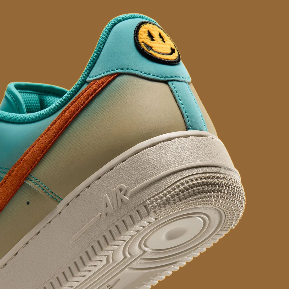 Heel detail, yellow smiley patch on teal tab, orange suede swoosh, AIR text and cream midsole, Holiday 2026 Collection