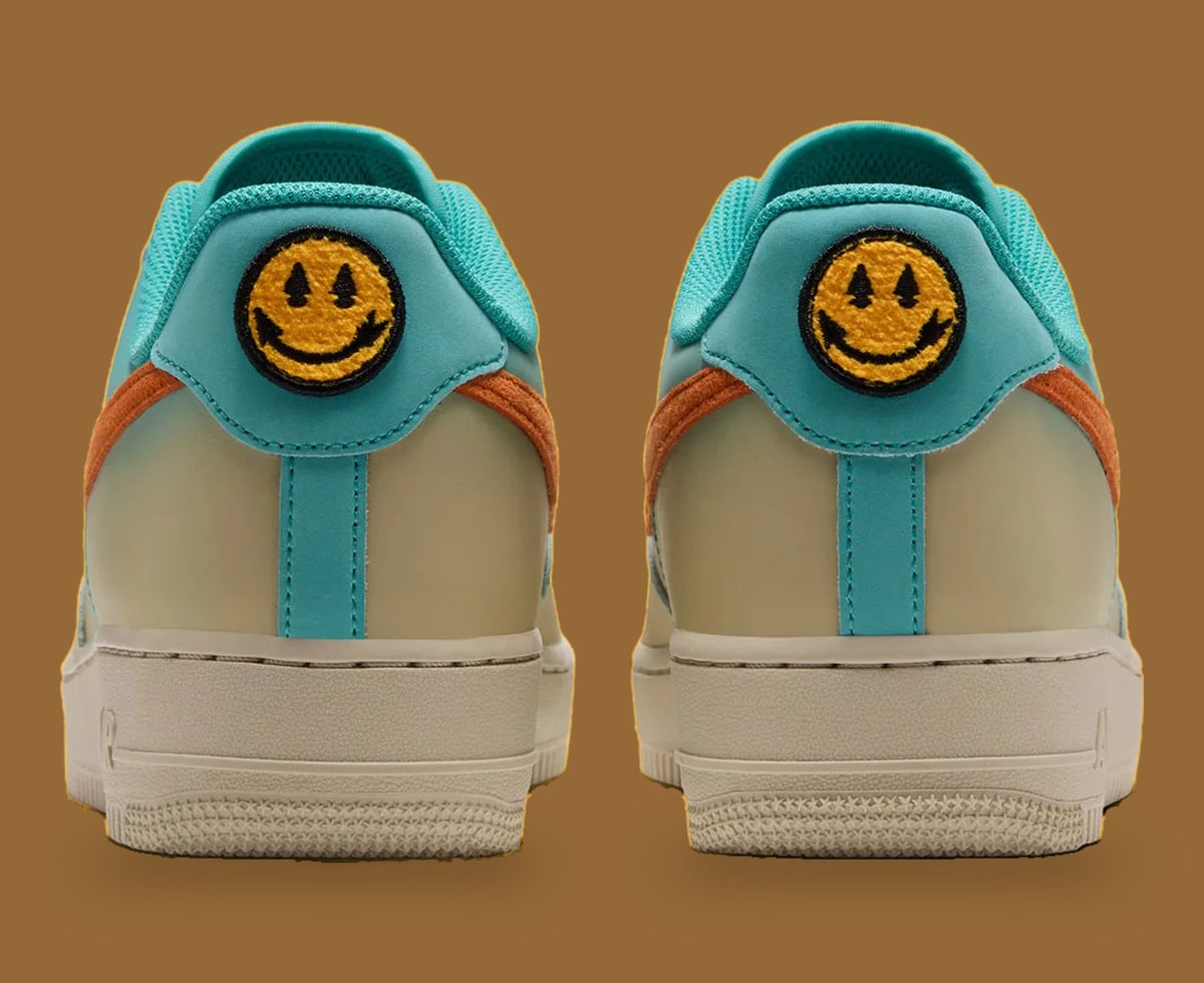 Heel view of pair, yellow smiley patches on teal heel tabs, orange swoosh edges, cream midsole, Holiday 2026 Collection