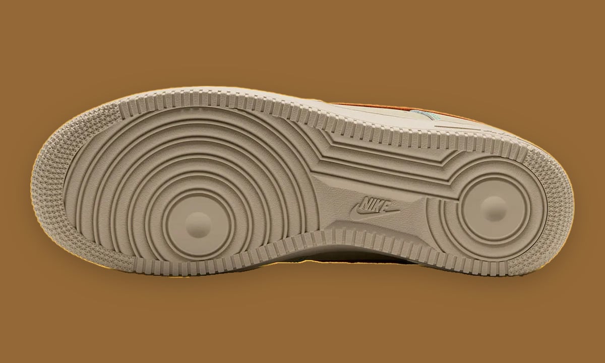 Outsole view, tan circular tread pattern, small Nike logo at the arch, brown background, Holiday 2026 Collection