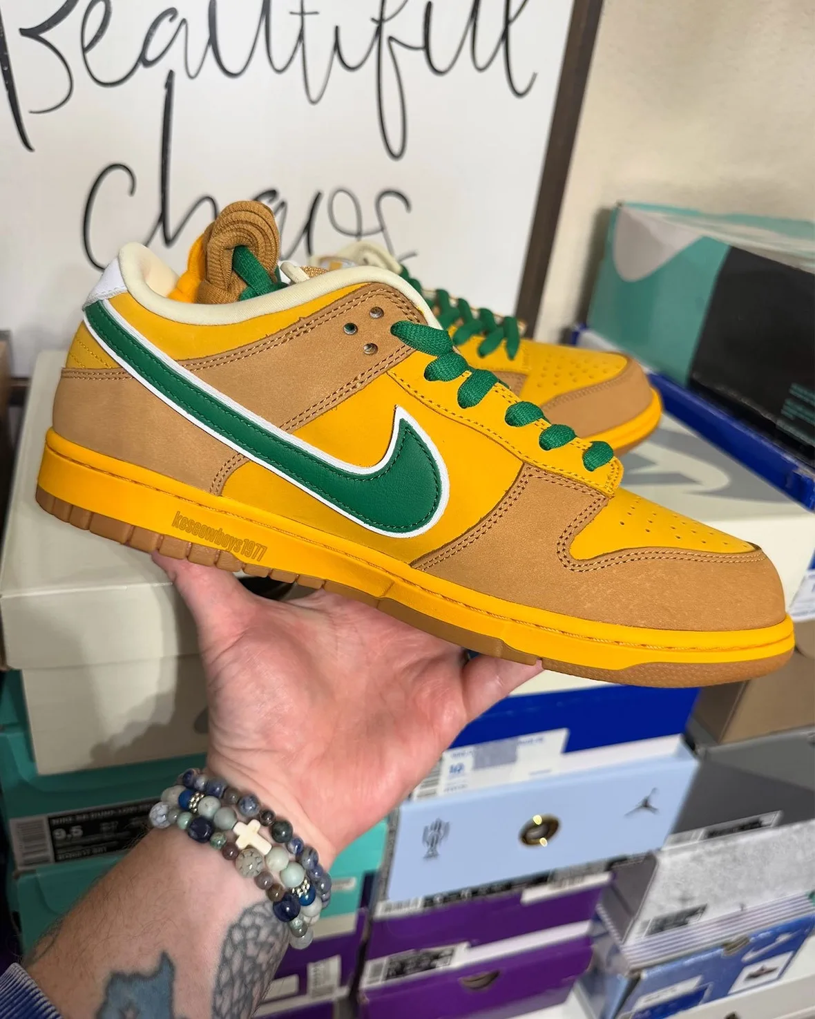 Medial in-hand view, green swoosh, yellow and tan panels, green laces, gum sole, Shout